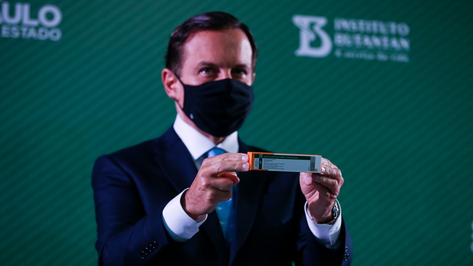 Photo of a masked Joao Doria holding a box of the CoronaVac vaccine during a press conference