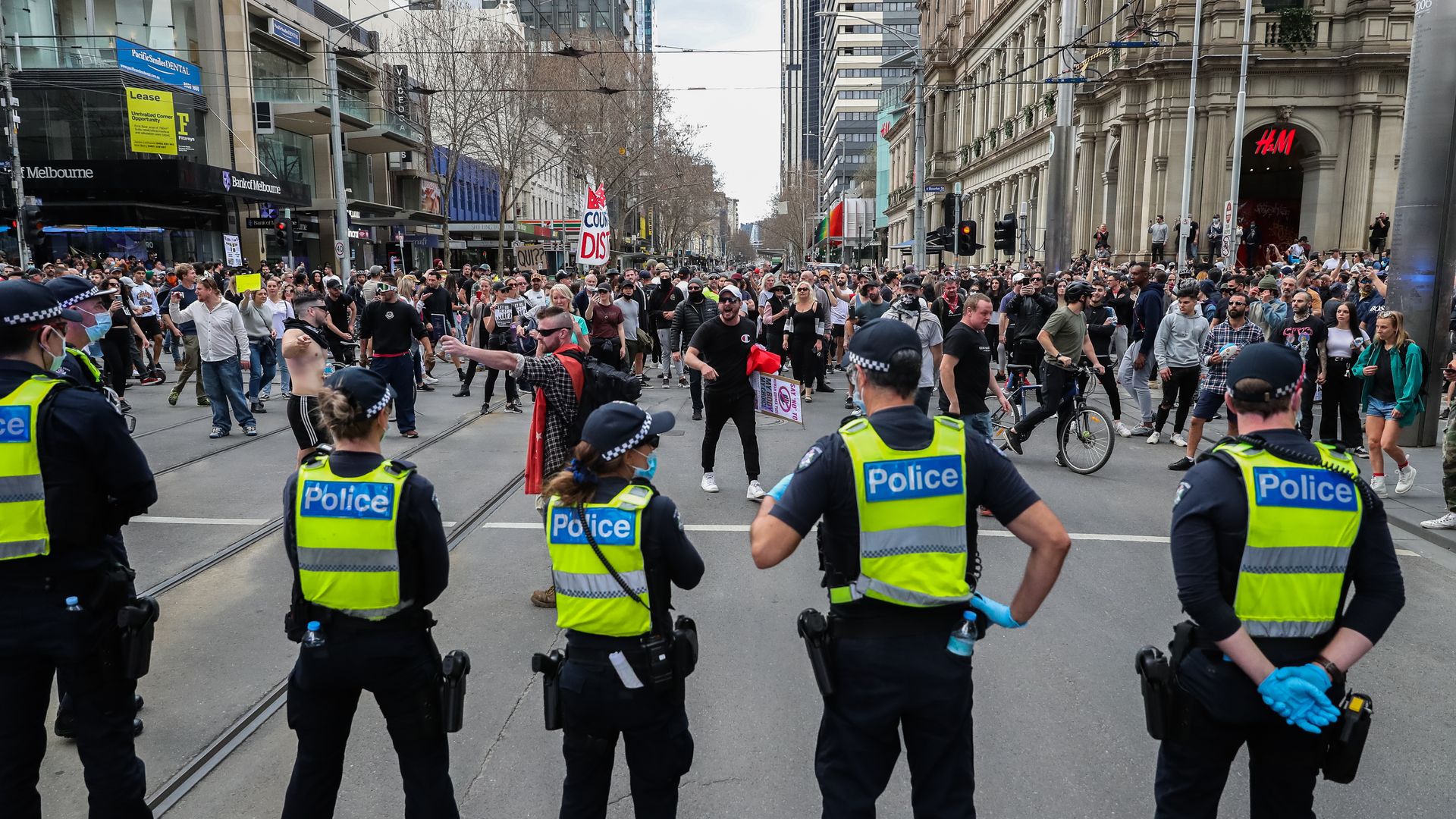 Picture of protesters in Australia, a line of police stands in front of the camera