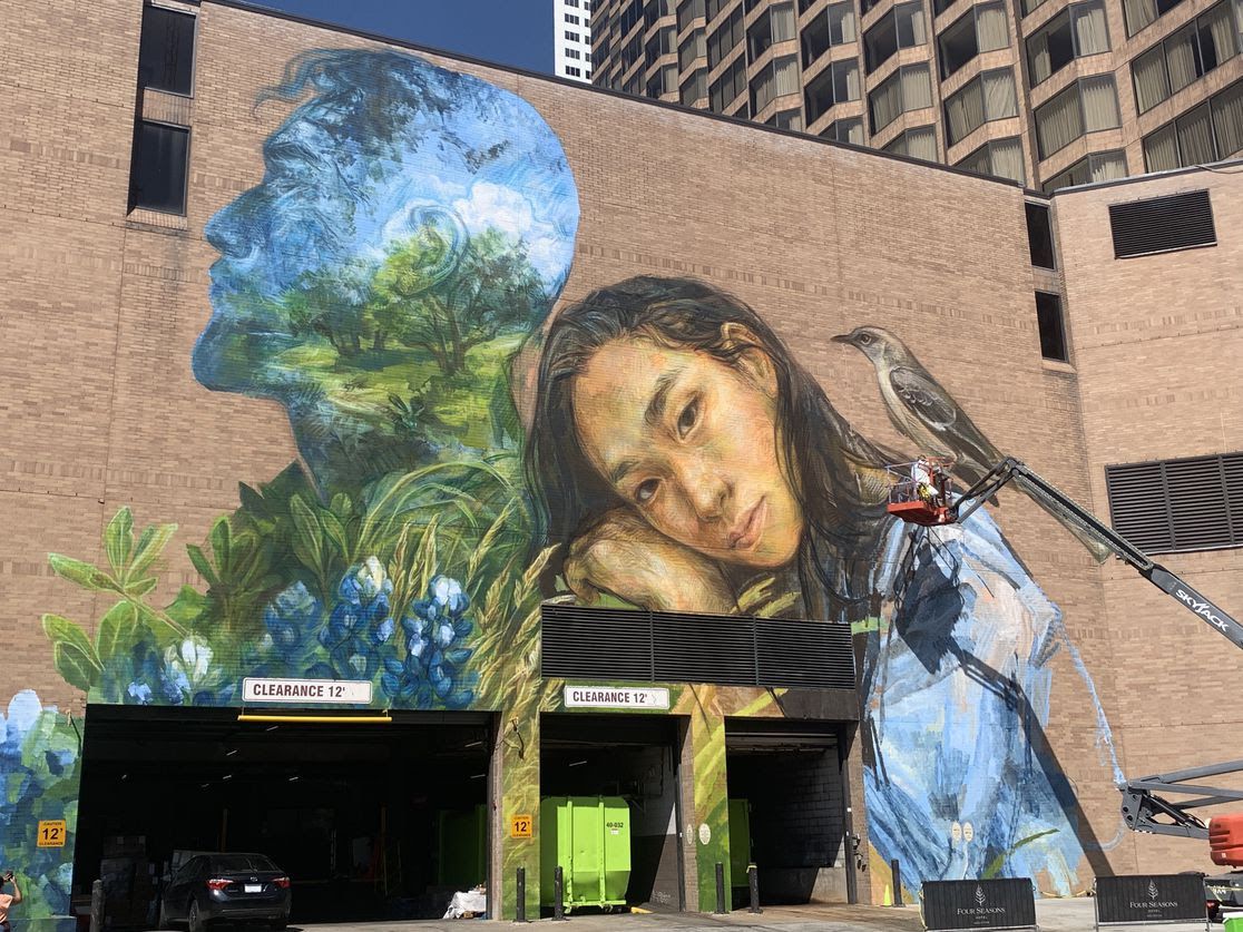 Photo of a mural with two human figures and nature. 