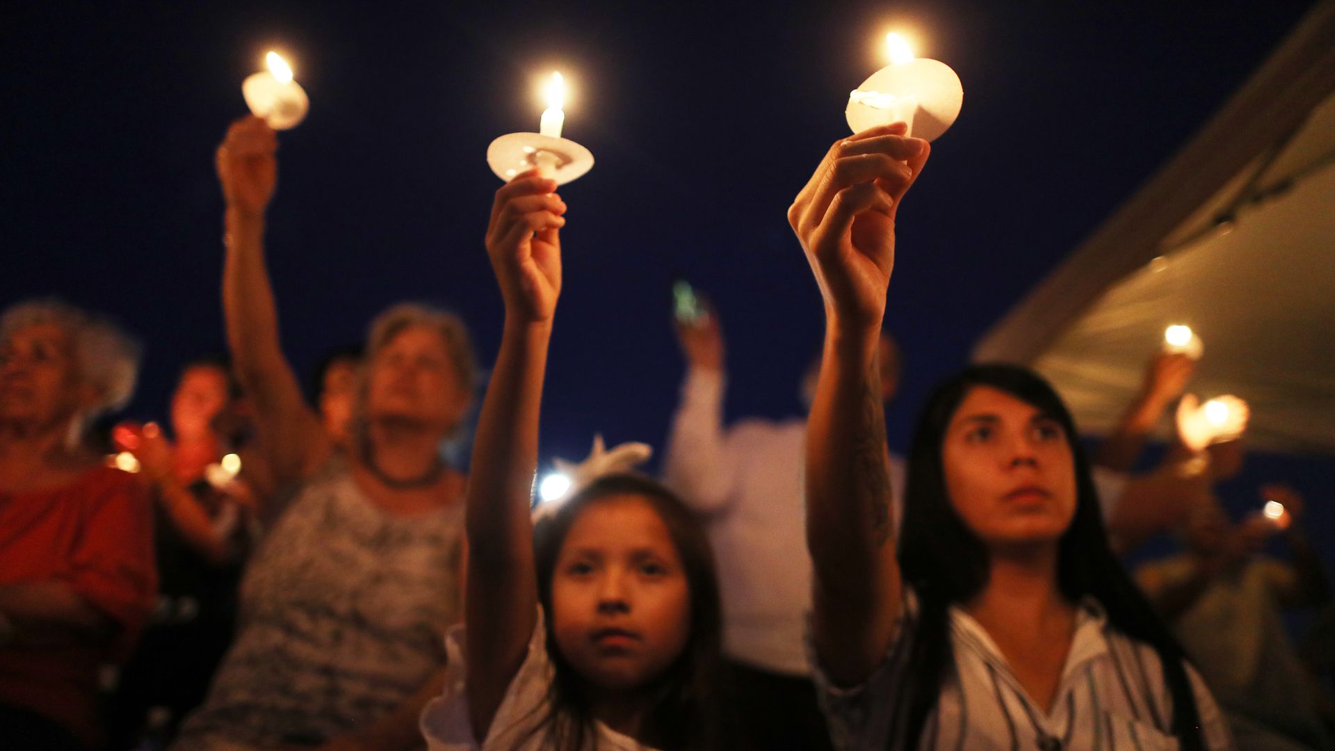 Mourners holding up candles at a vigil for those lost in El Paso.