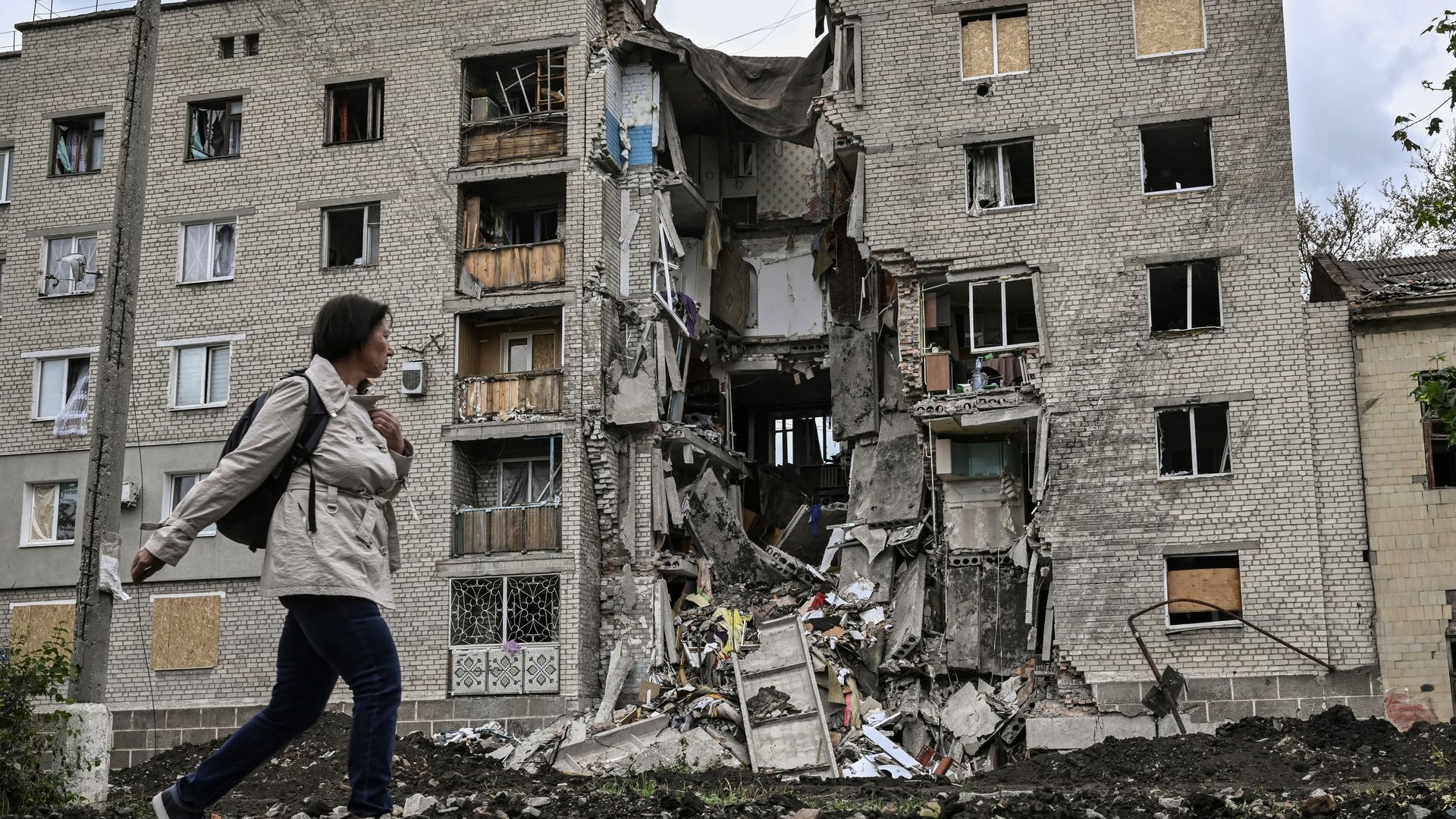 A woman walks by a destroyed apartment building in Bakhmut in the eastern Ukranian region of Donbas on May 22, 2022