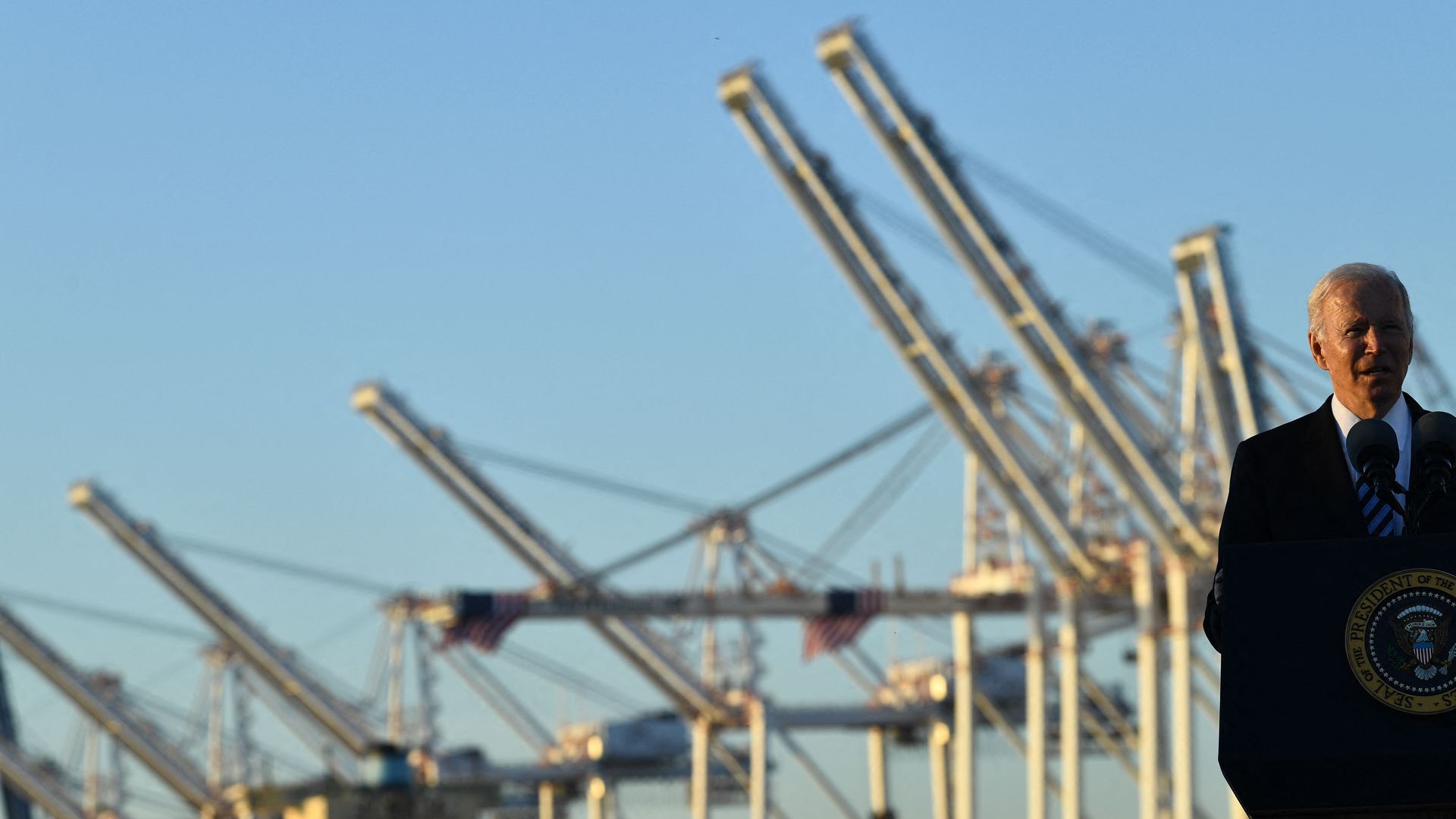 President Biden is seen speaking before sets of cranes at the Port of Baltimore.