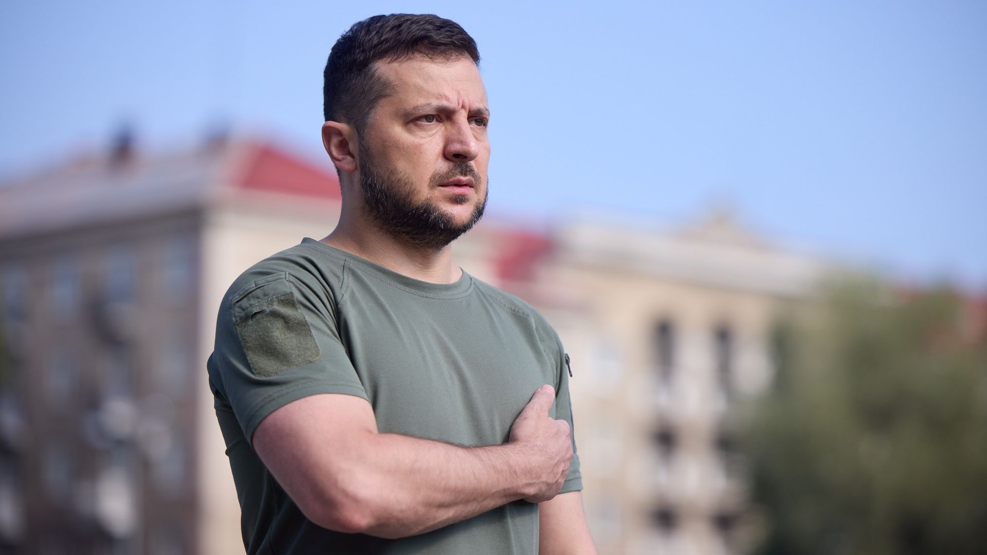 Ukrainian President Volodymyr Zelenskyy stands with one arm across his chest outside Hetman Petro Sahaidachnyi National Ground Forces Academy in Lviv, Ukraine on August 18, 2022.