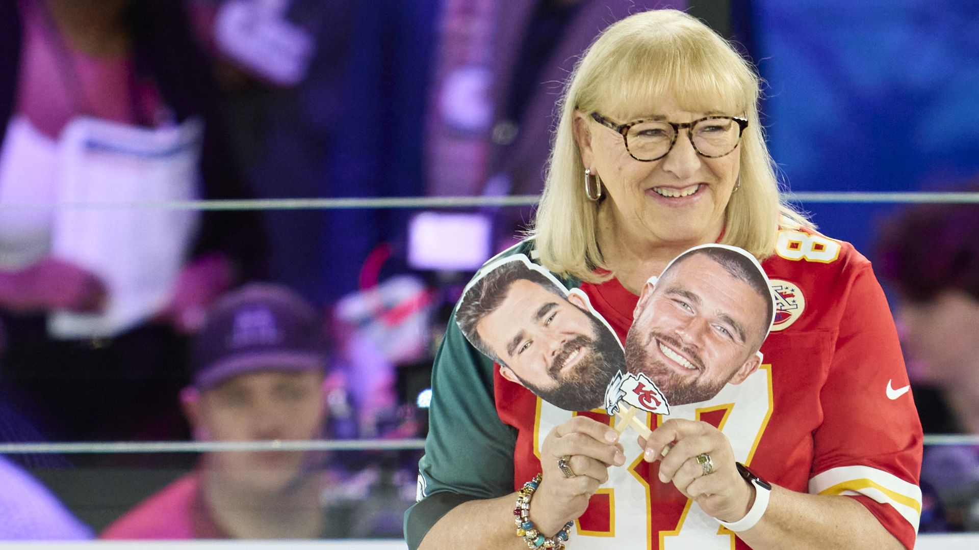 Donna Kelce, the mother of two NFL players, holds up photos of them.