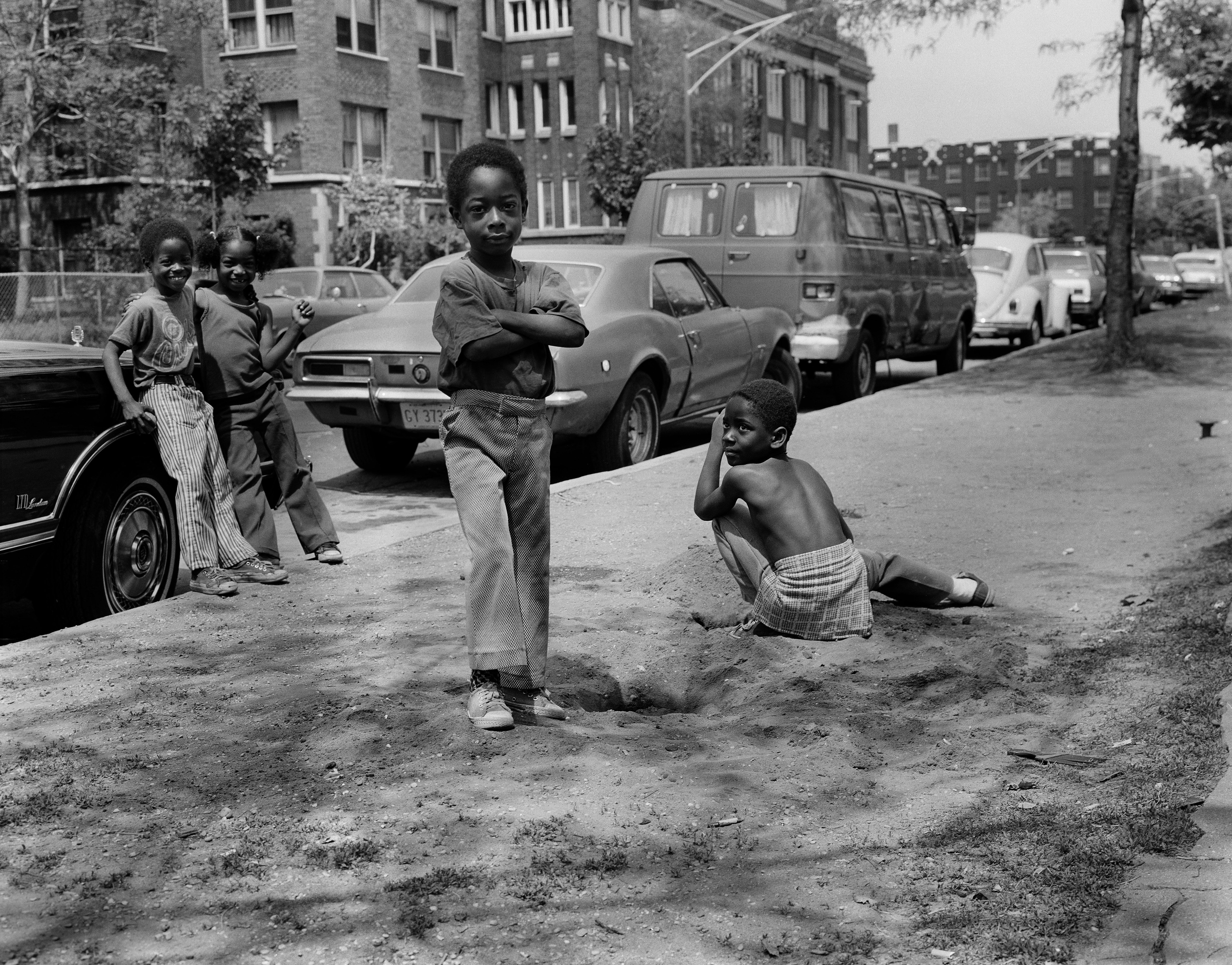 Photo of kids posing for the camera while playing by a street 