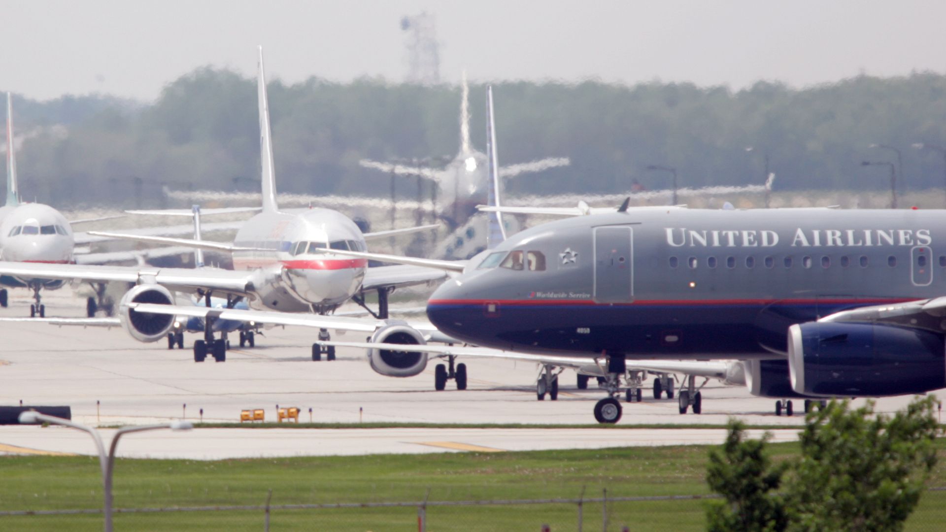 Planes on a runway with a blue and navy United Airlines plane in front.