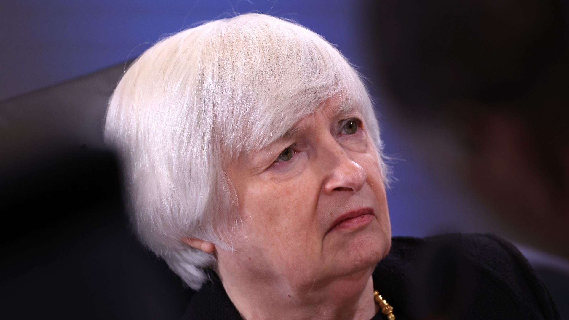A white haired lady, Janet Yellen, scowls at the distance