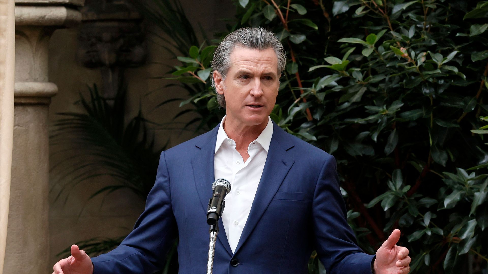 Gov. Gavin Newsom in a blue suit with his arms spread
