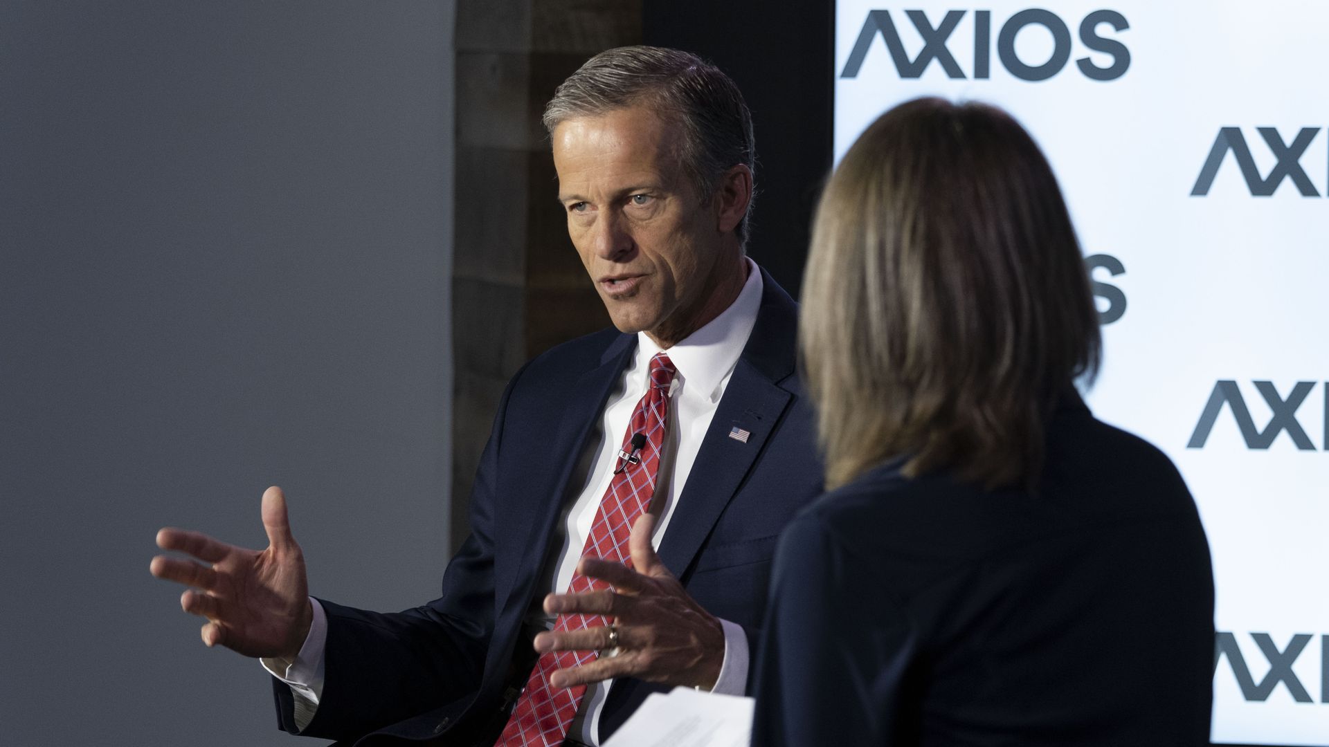 A man wearing a red tie speaks on stage