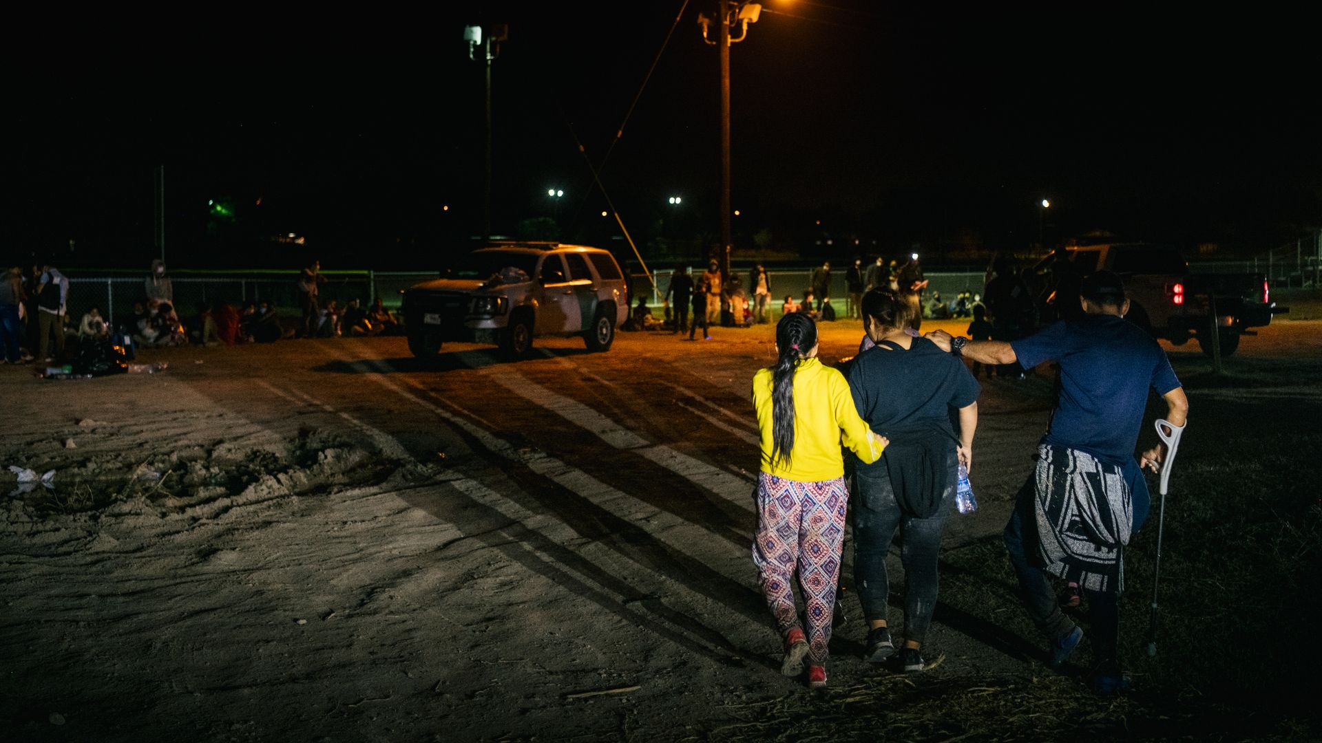 Photo of people walking toward DHS patrol cars under the cover of night