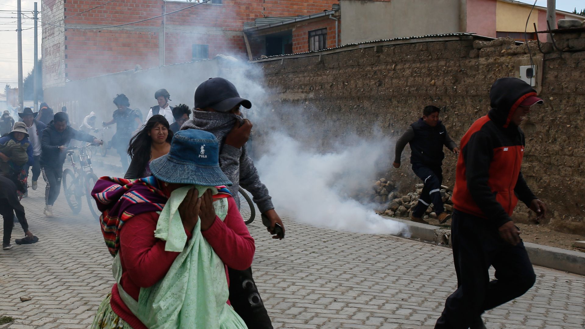 Supporters of Evo Morales run from tear gas as clashing with police during protests on November 19
