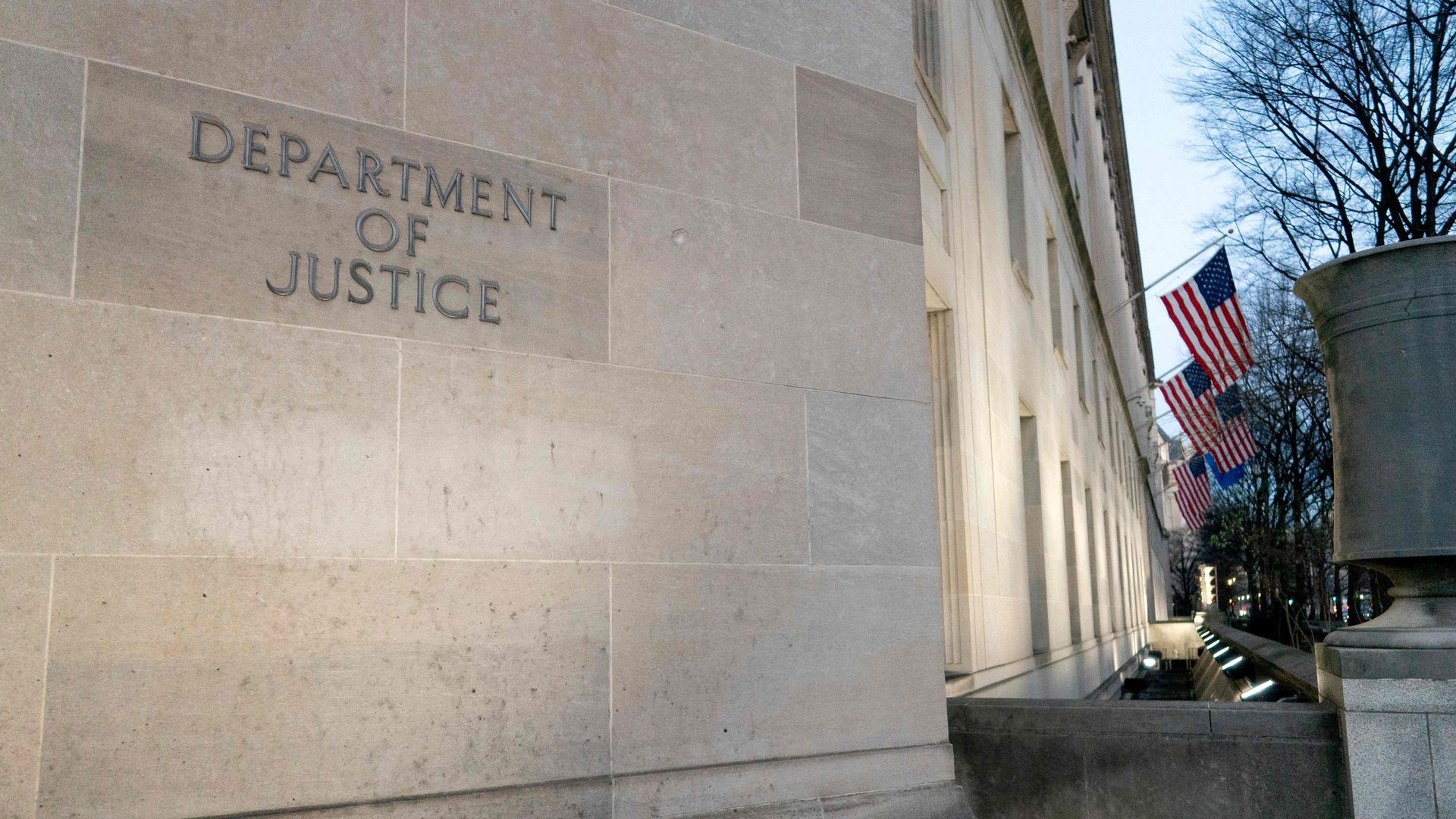 Photo of the Department of Justice building with American flags hanging at the top of the front entrance