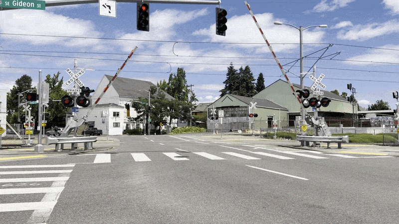 Animated gif shows rail crossing gates coming down on an urban street.