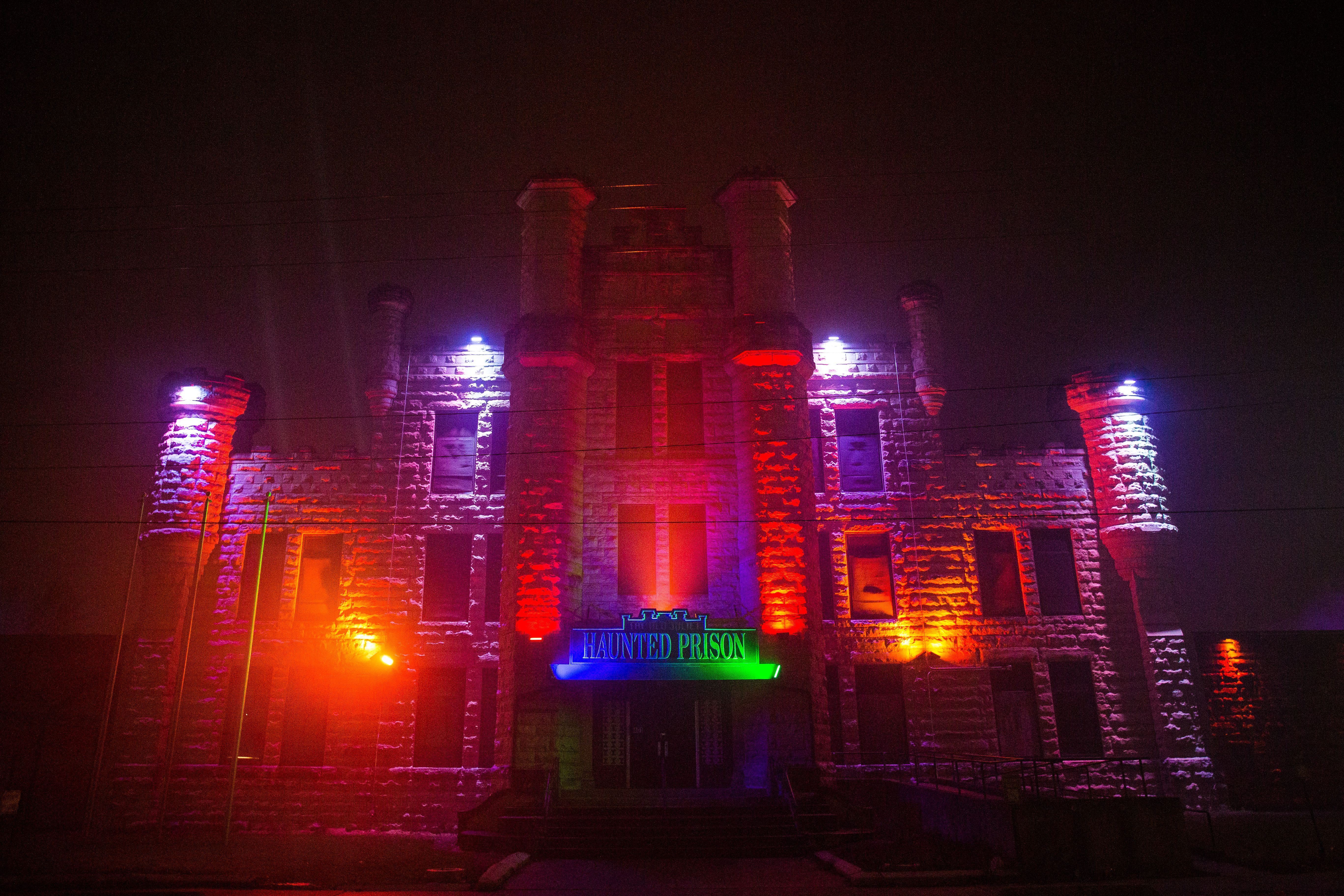 Photo of the front of an old prison lit up with lights. 