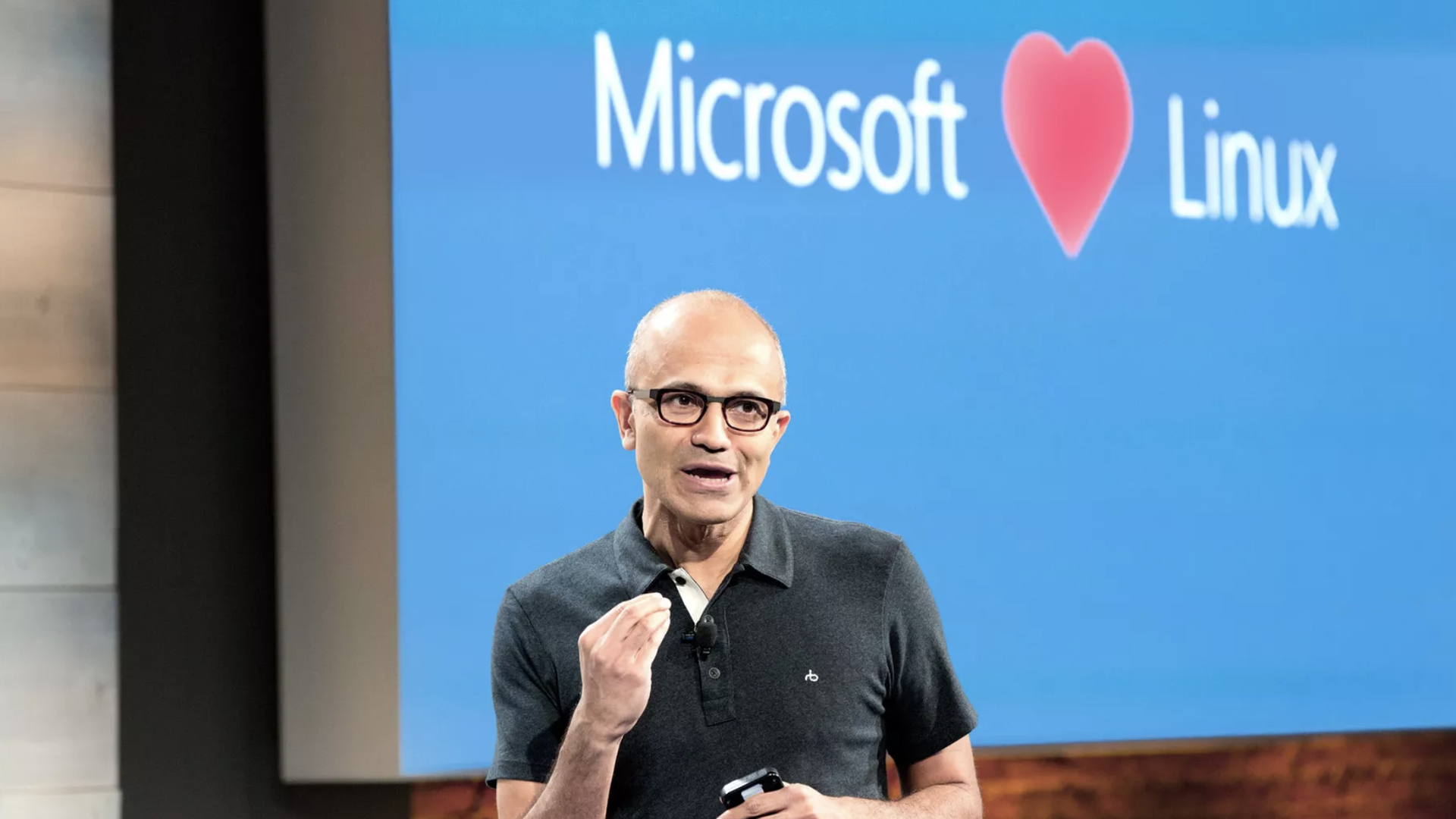 Microsoft CEO Satya Nadella in front of a sign reading "Microsoft Loves Linux"