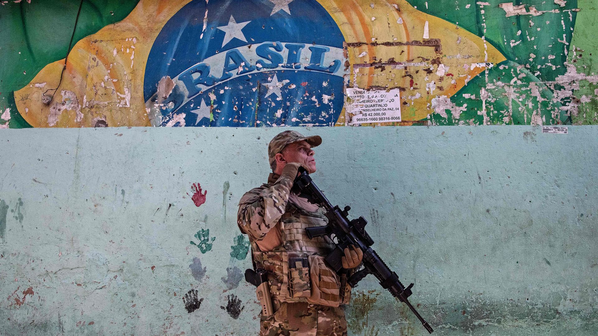 A Brazilian soldier stands while holding a large rifle during an anti-drug operation. 