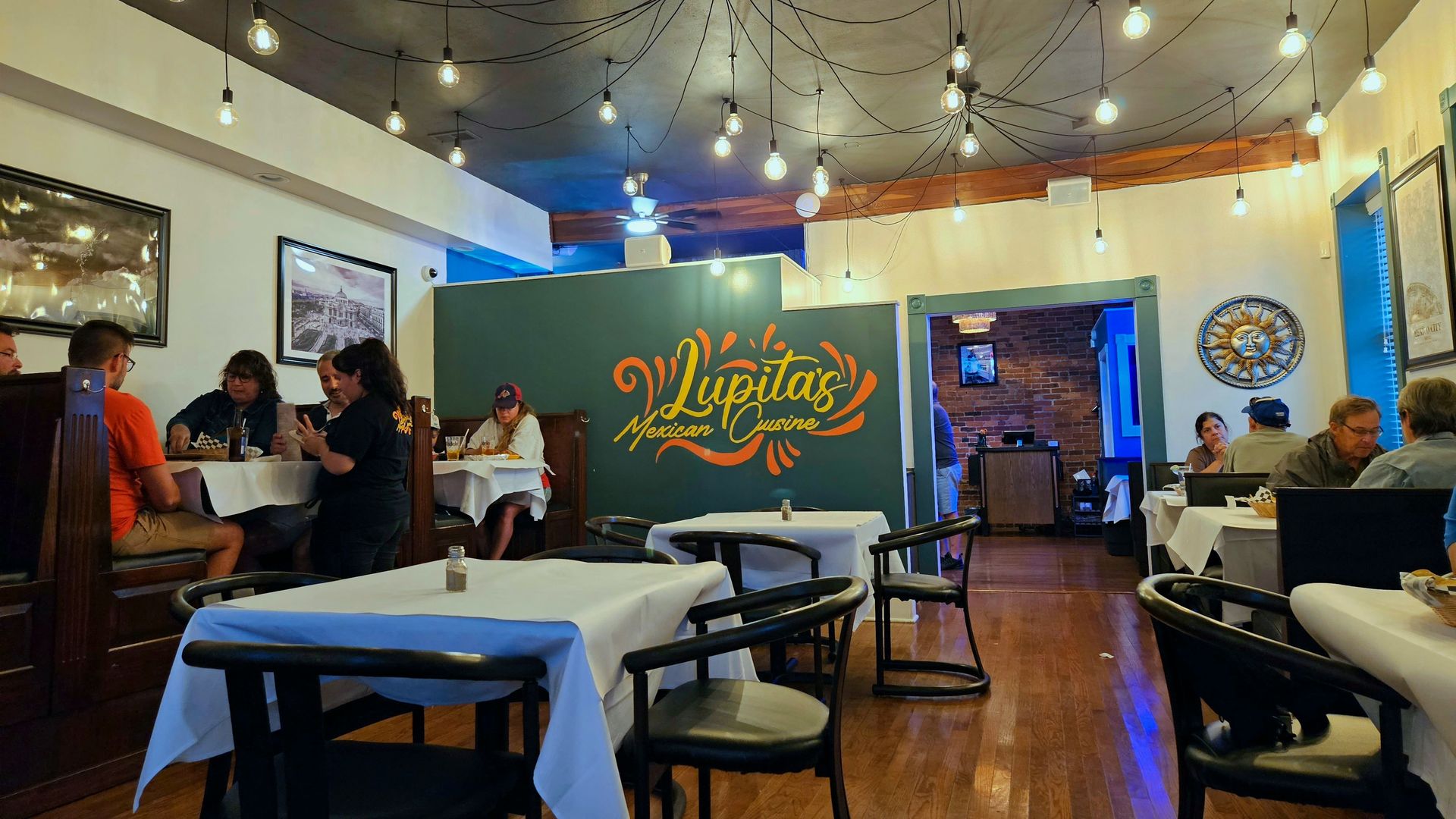 A mural reads "Lupita's Mexican Cuisine" inside the restaurant dining area, with lights strung on the ceiling