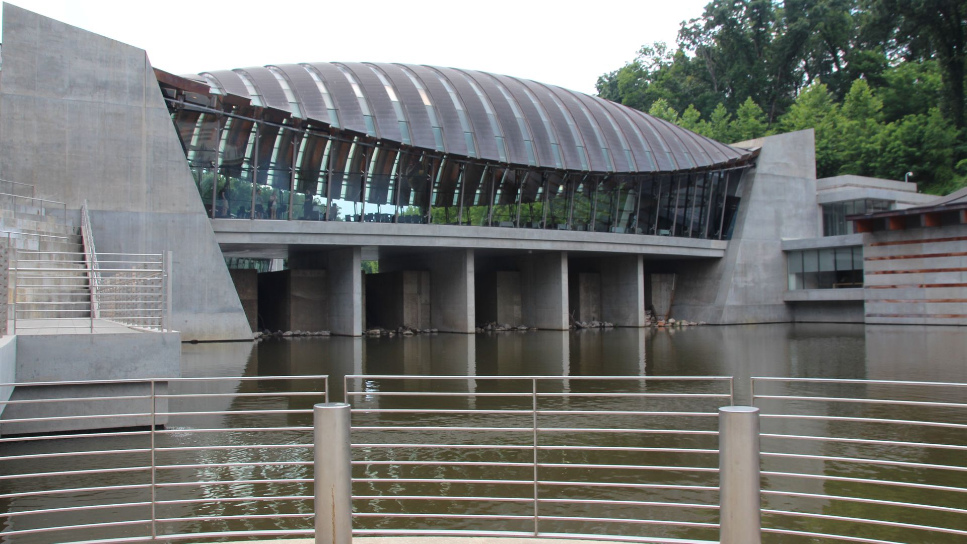 A view of the Crystal Bridges art museum from the outside, surrounded by a body of water