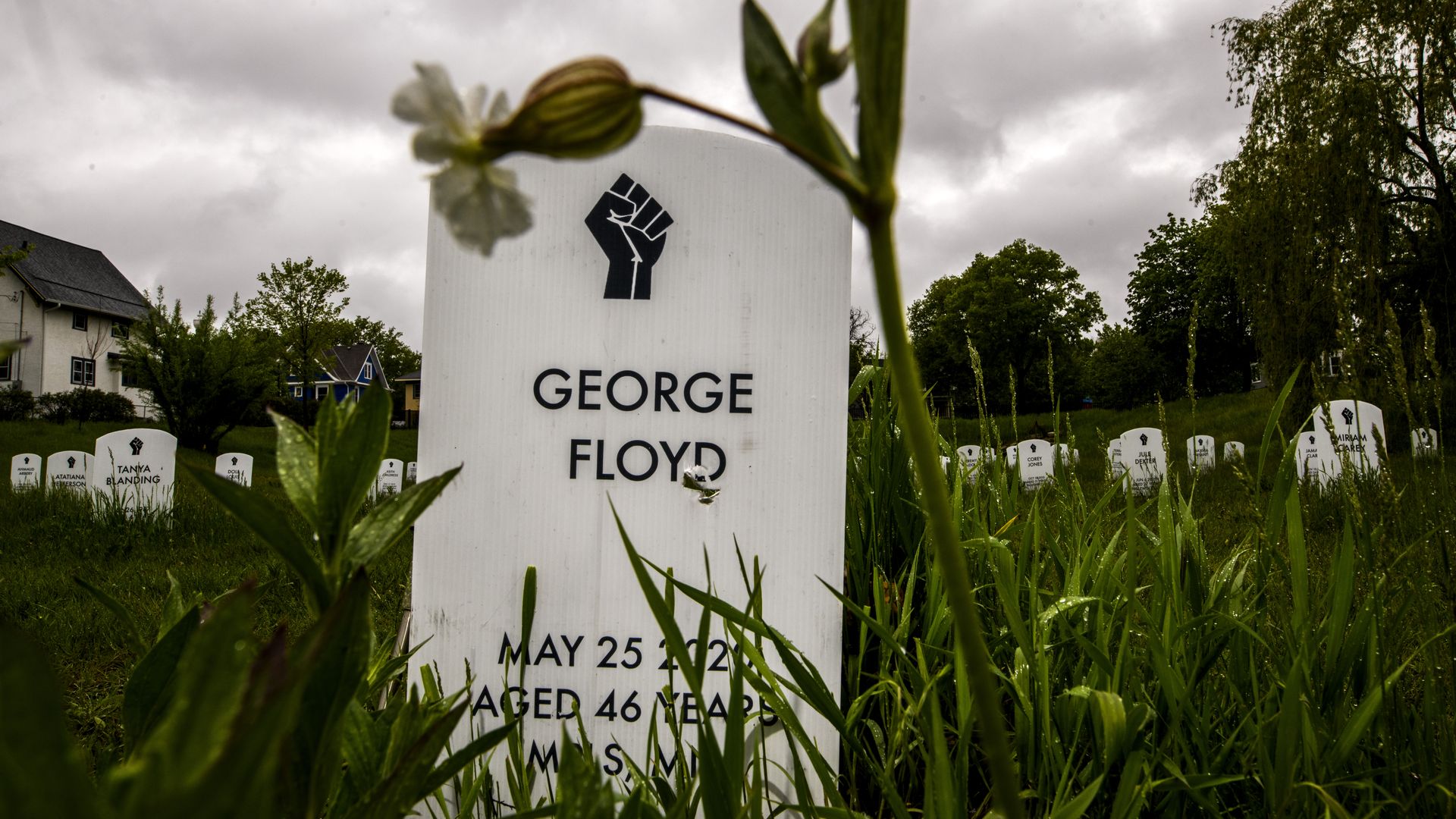 Photo of a white gravestone with George Floyd's name and the image of a fist engraved on it