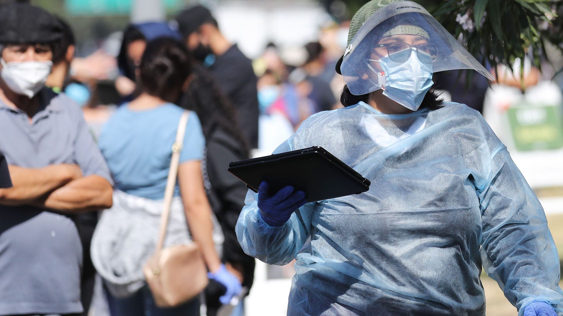 A worker in personal protective equipment (PPE) helps check in people at a COVID-19 testing center in Los Angeles, California. Photo: Mario Tama/Getty Images