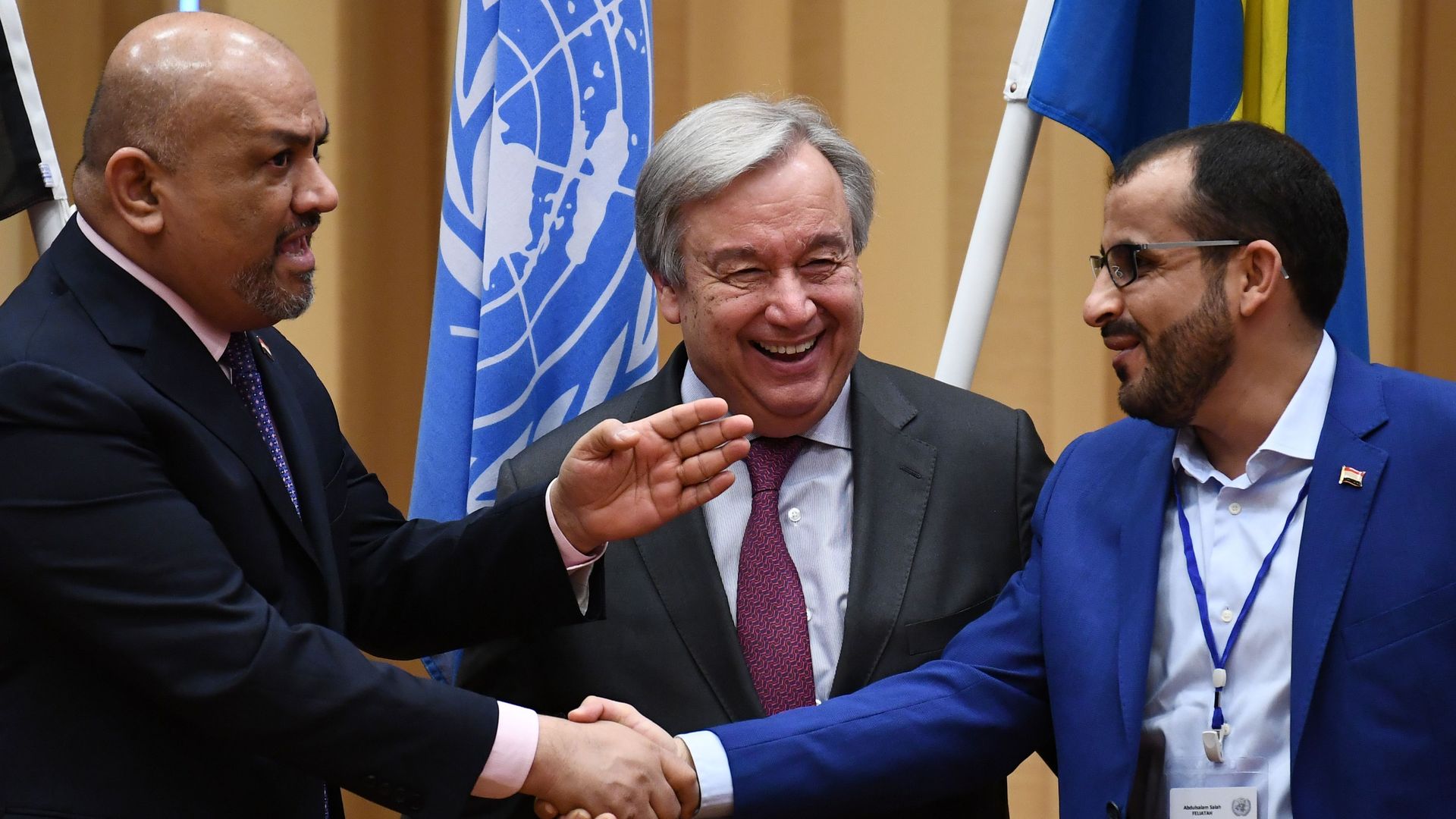 Yemen's foreign minister Khaled al-Yamani (L) and rebel negotiator Mohammed Abdelsalam (R) shake hands under the eyes of United Nations Secretary General Antonio Guterres during peace consultations 