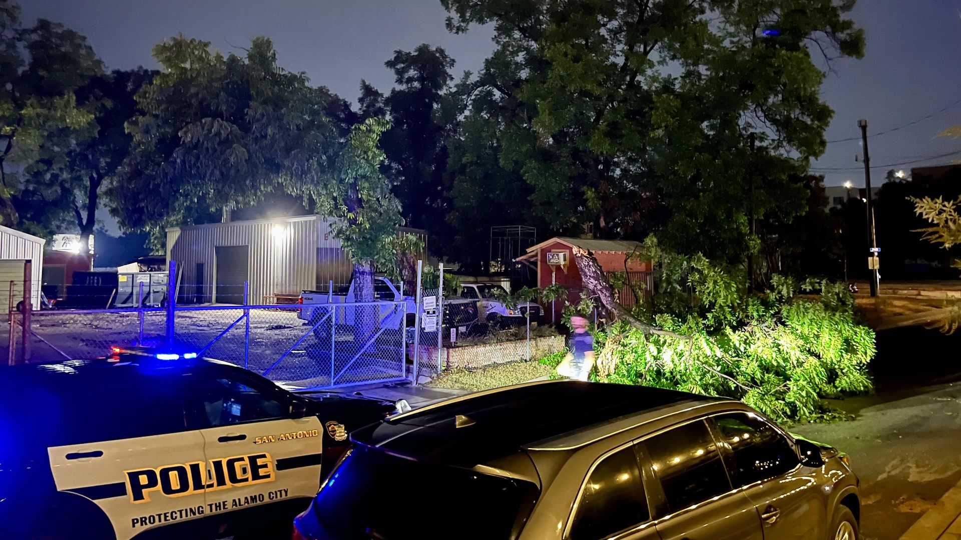 A San Antonio police officer moves a tree out of the road outside The Lonesome Rose on Friday night.
