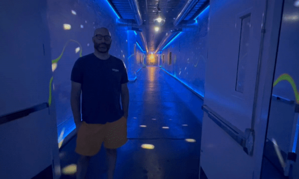 Video of a man standing in a hallway with flashing lights. 