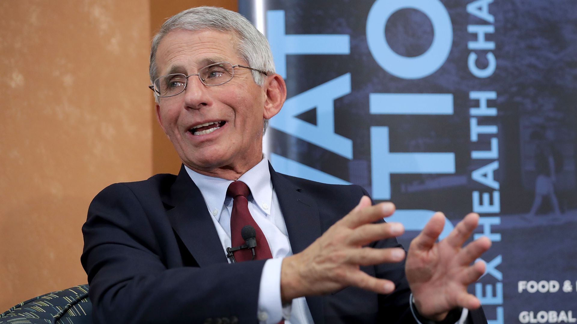 NIAID chief Anthony Fauci speaking at another panel, sitting down and gesticulating with his hands