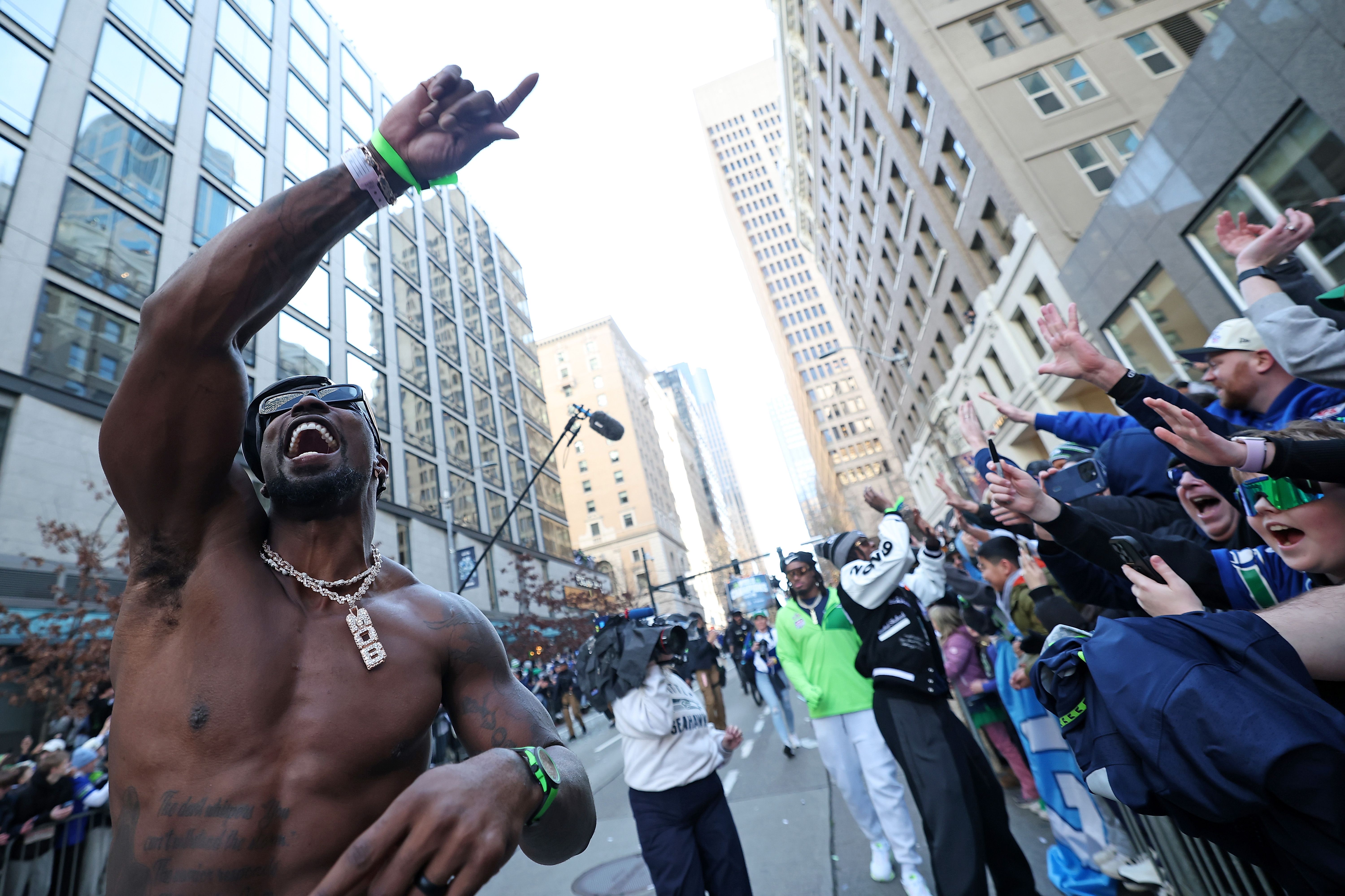 A shirtless DeMarcus Lawrence celebrates with fans during the Seahawks Super Bowl LX parade.