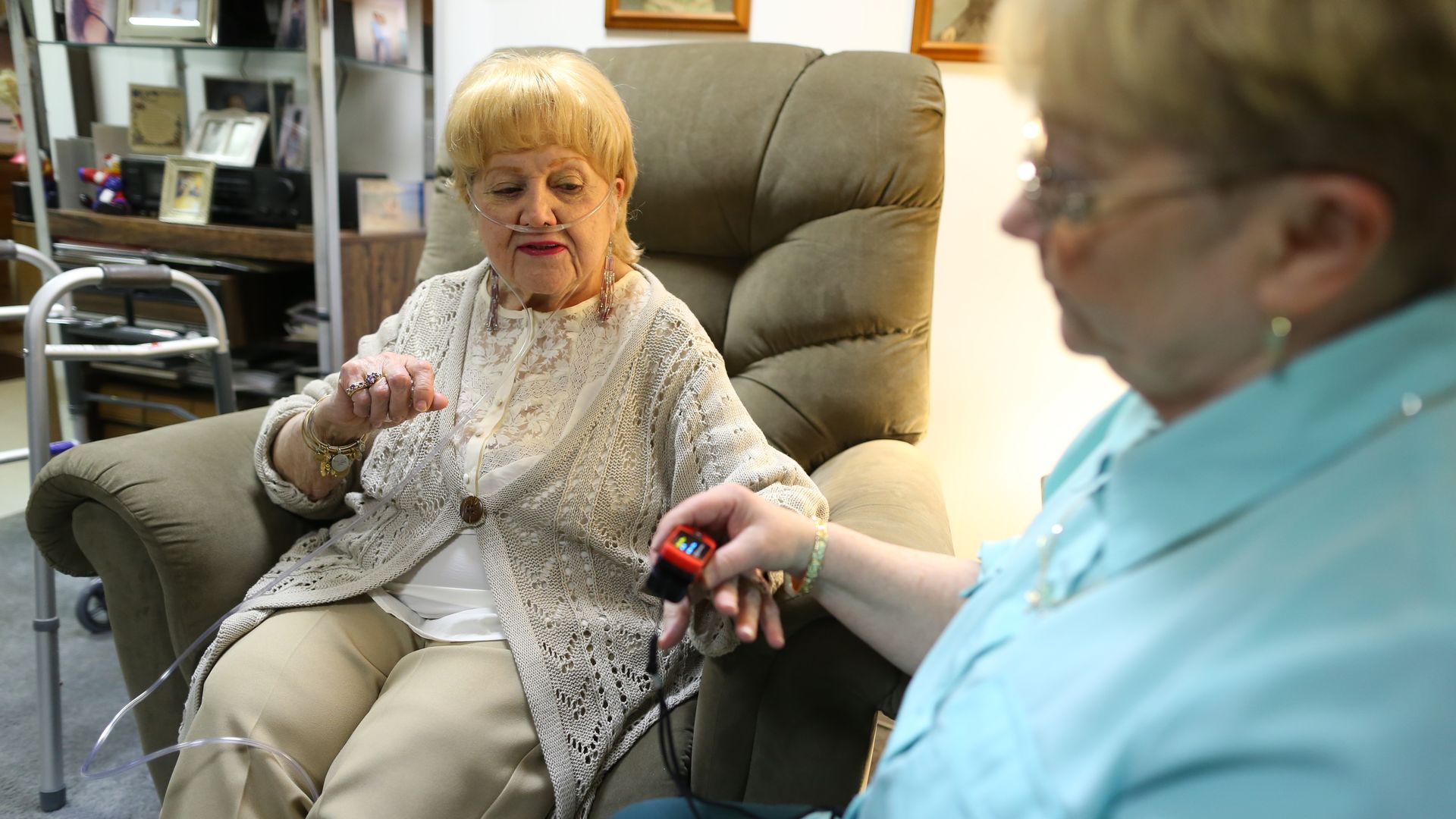 A patient with an oxygen tank gets observed by a nurse.