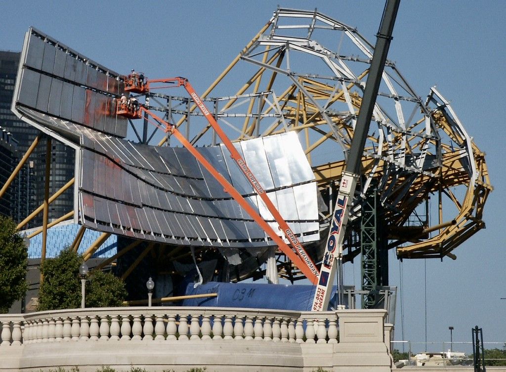 Metal being place on a steel structure by a person in a red crane.