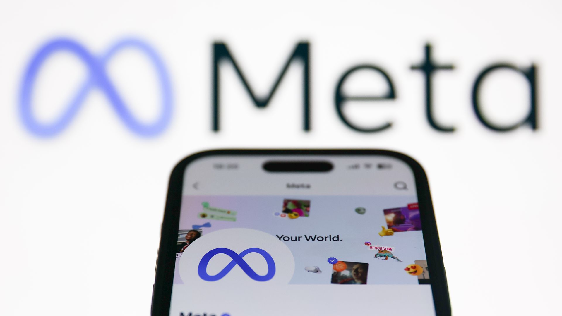 An image of Meta's logo on a backdrop with a phone in the foreground 