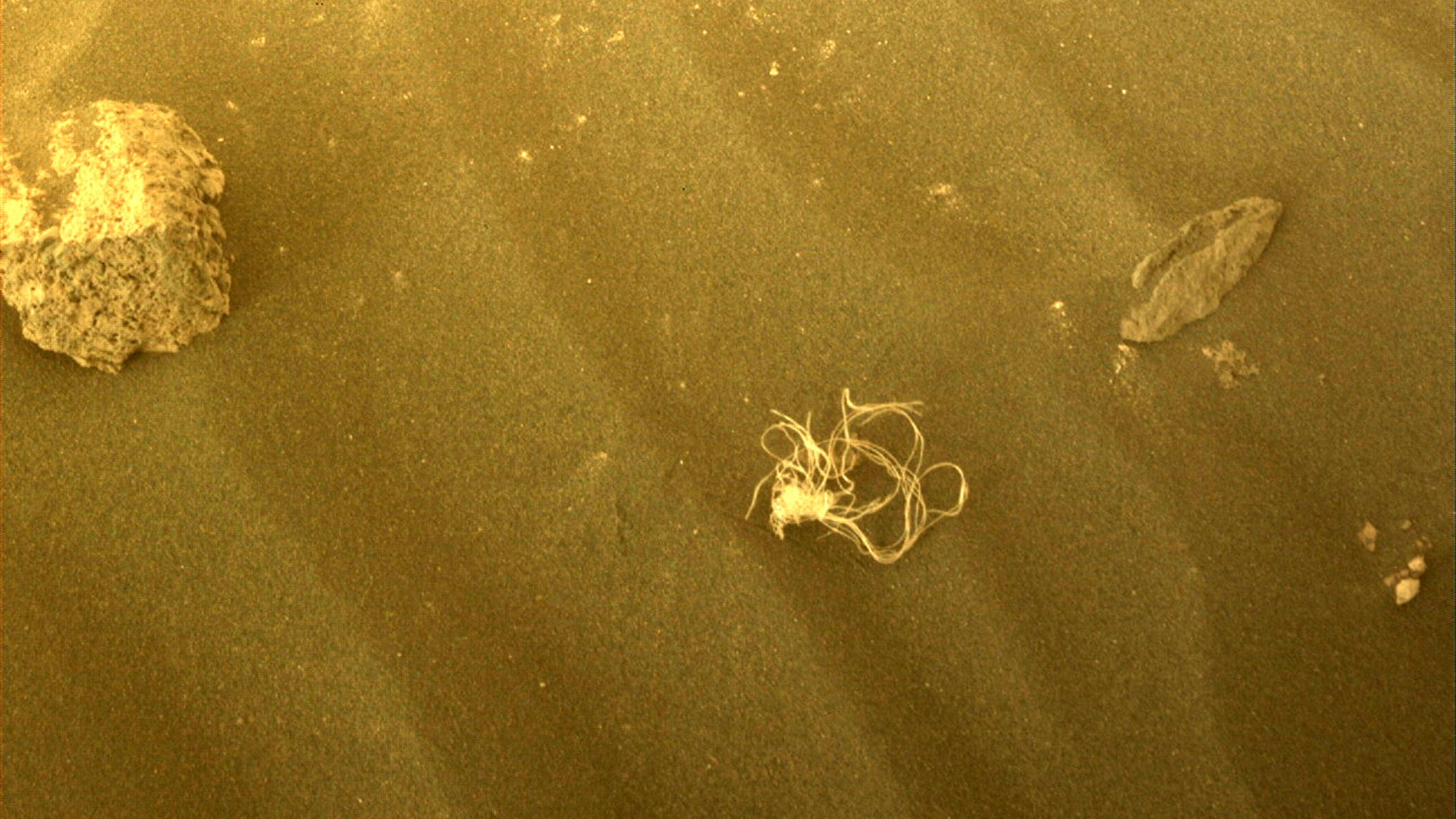 A piece of debris on what looks like sand on mars shining in yellow