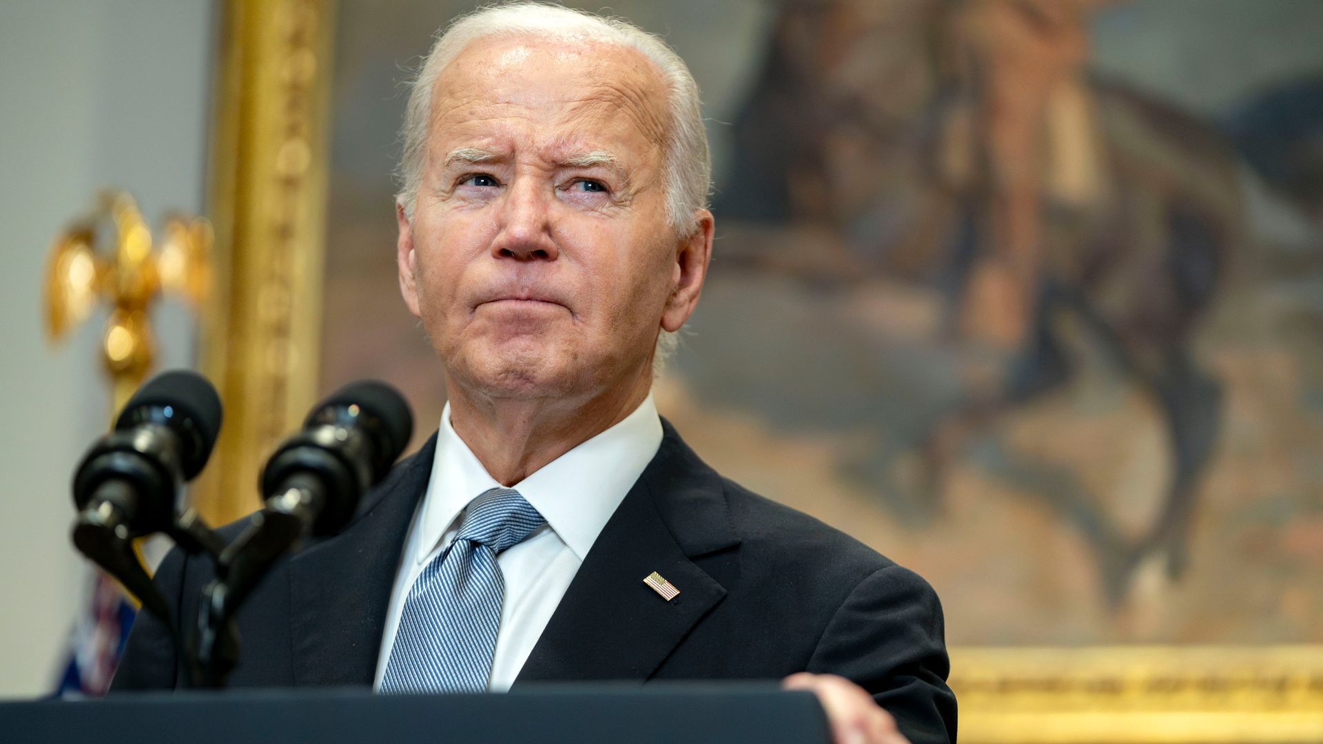 President Biden looks away while standing at a podium. 