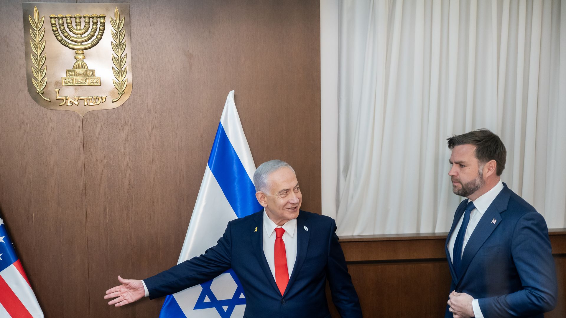 Benjamin Netanyahu gestures with his right arm to JD Vance with Israeli and U.S. flags in the background.