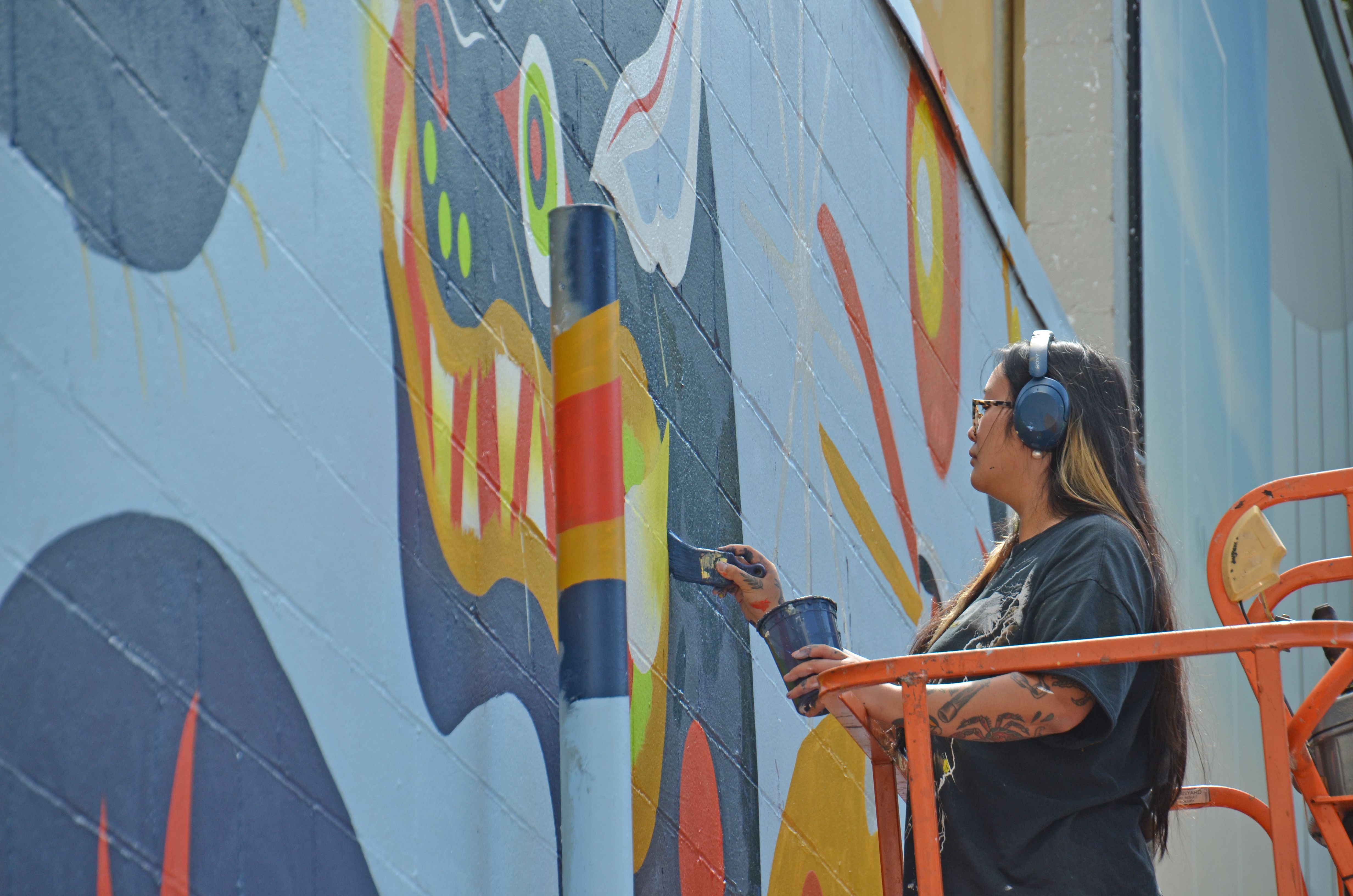 A muralist paints on the side of a building in Seattle. 