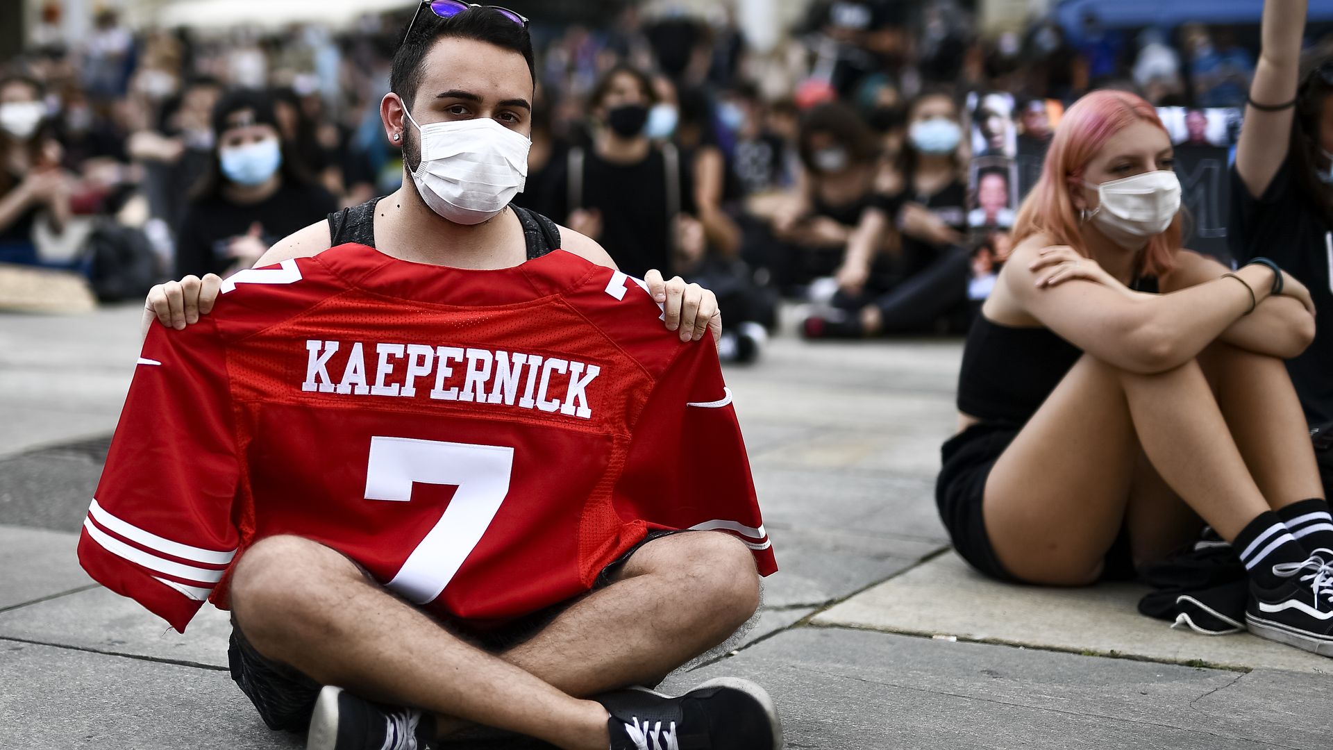 A protester holds a red jersey with the number 7 and "Kaepernick" on it 