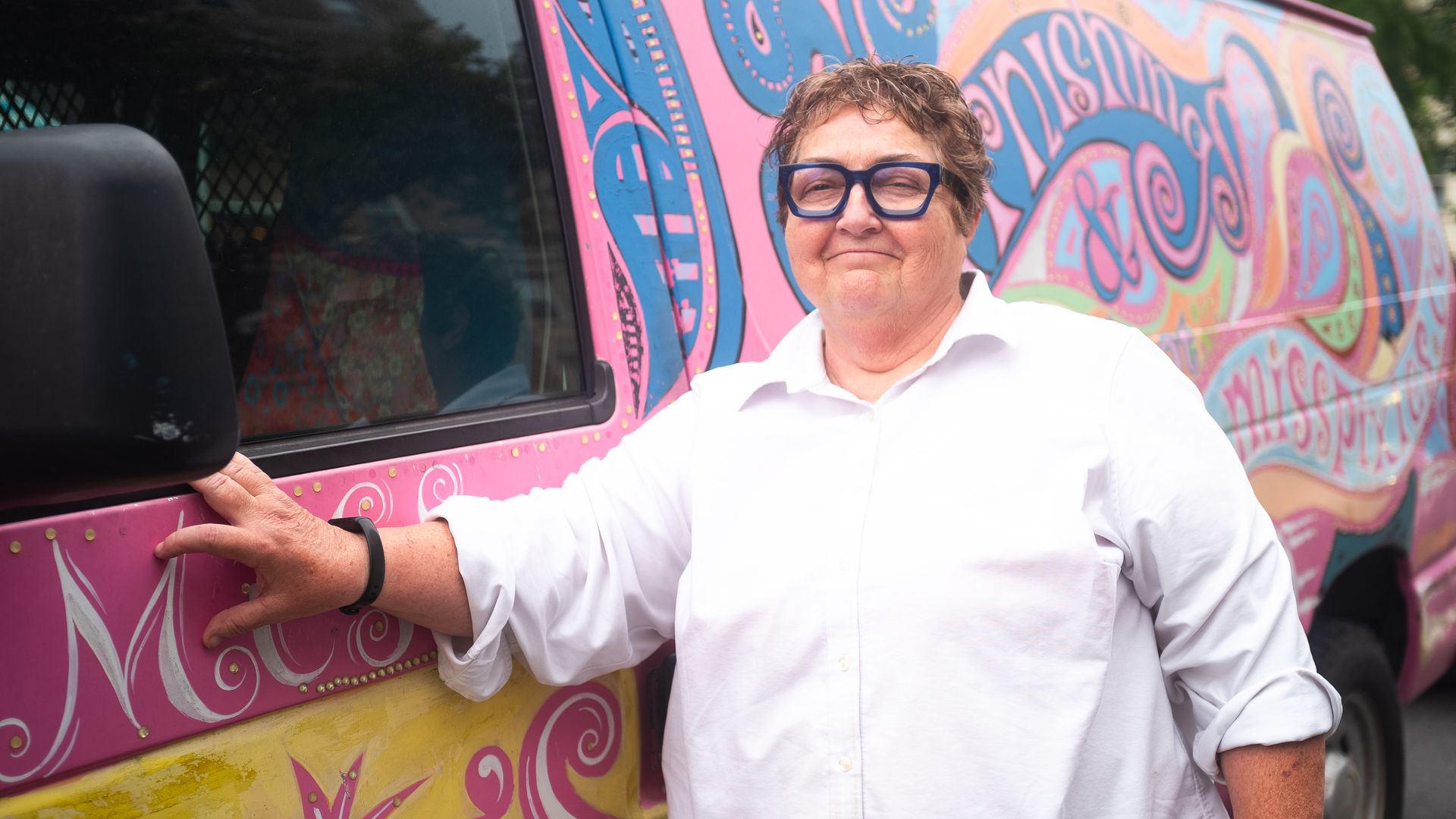A photo of a woman standing in front of a colorful van.