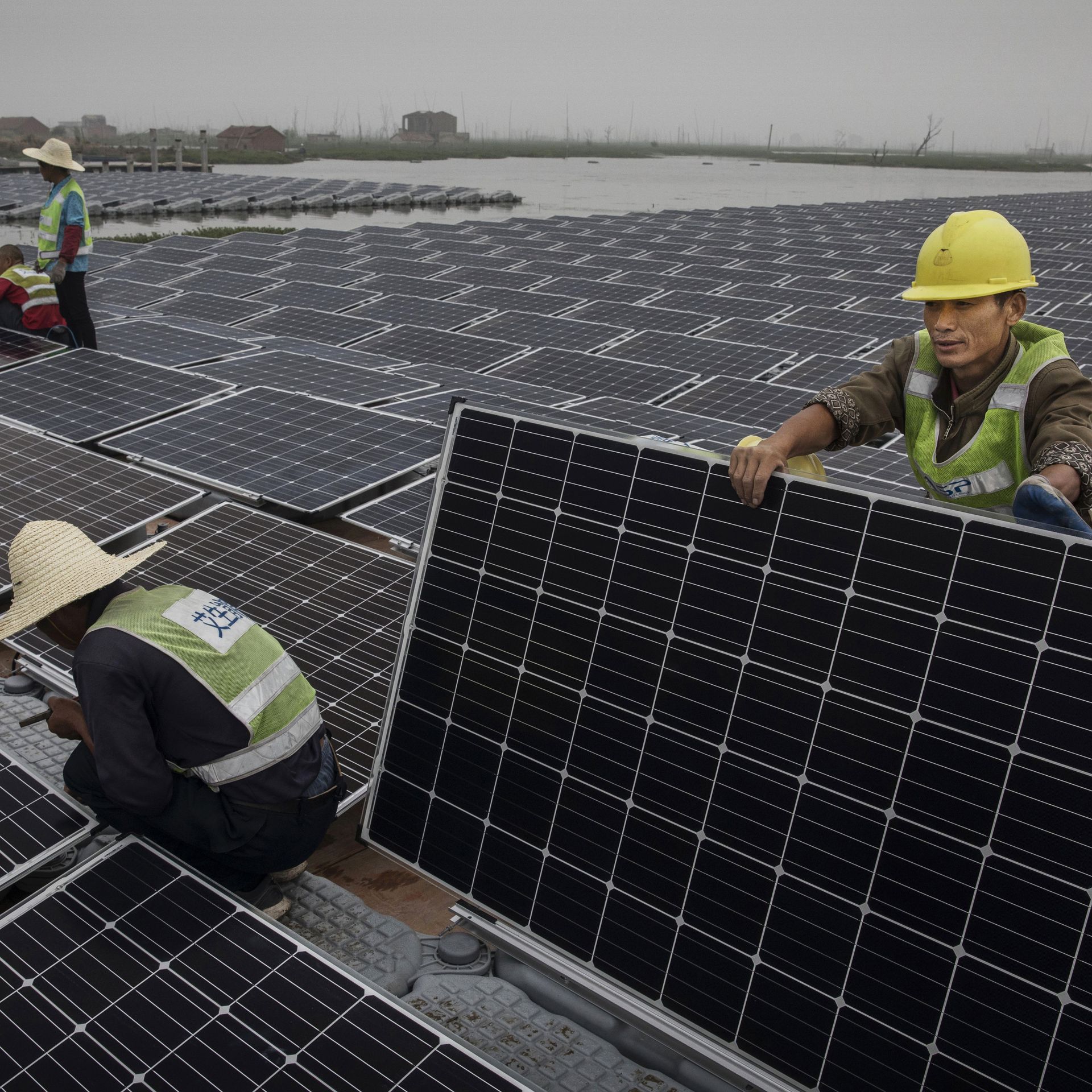 Chinese workers prepare panels that will be part of a large floating solar farm project under construction