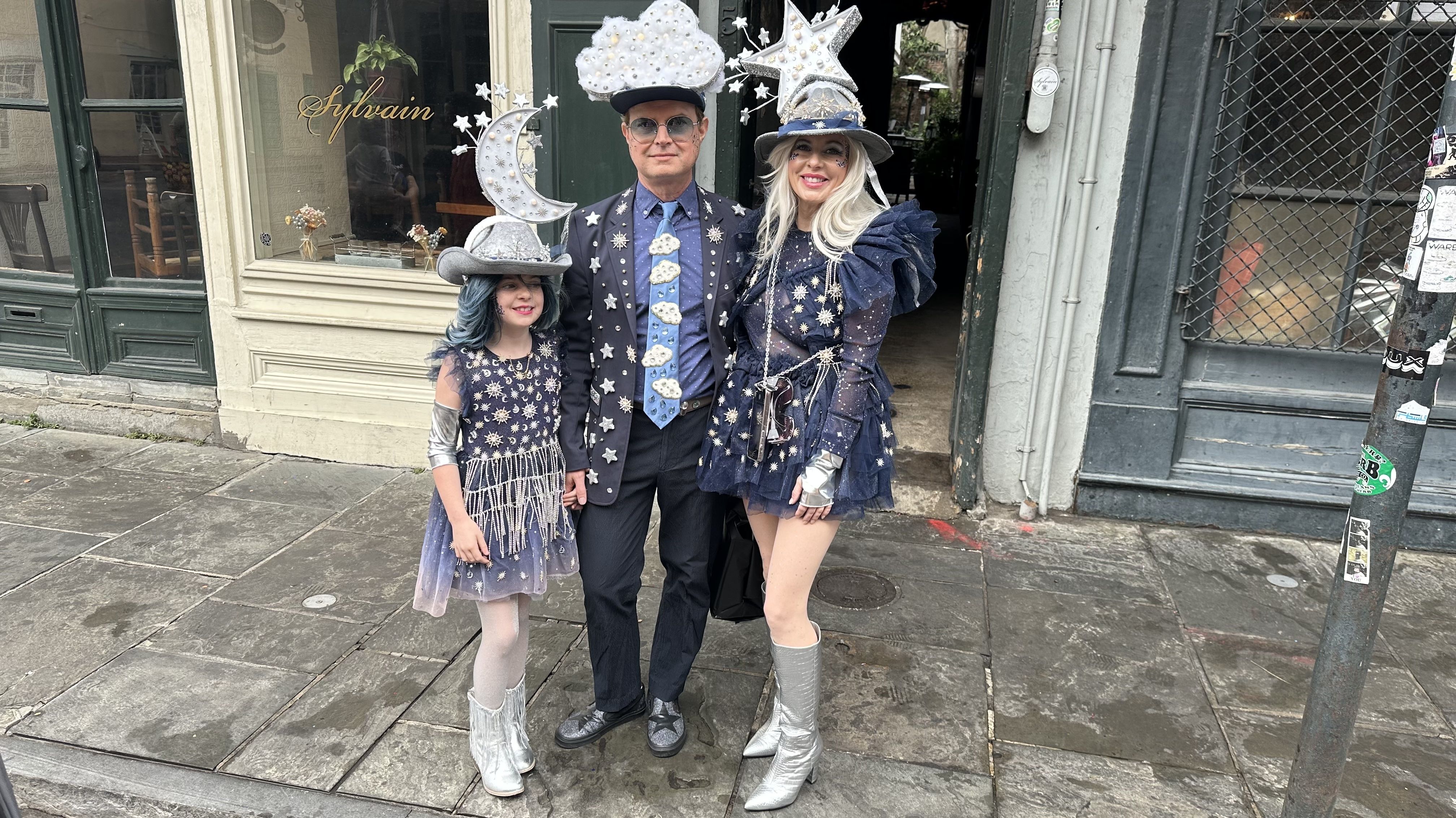 A couple poses for a photo with a young girl. One is dressed as a cloud, another as a moon and the third as a star.