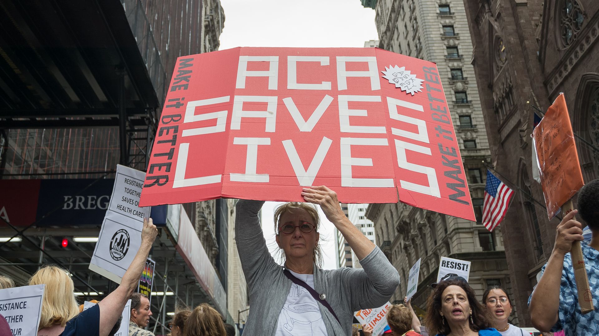 A demonstrator holds a sign that reads, "ACA Saves Lives"