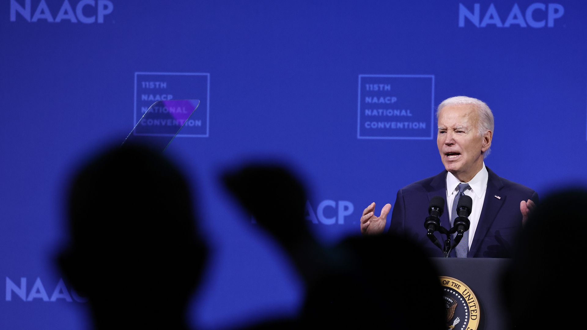 biden speaks in front of a blue screen with the NAACP logo