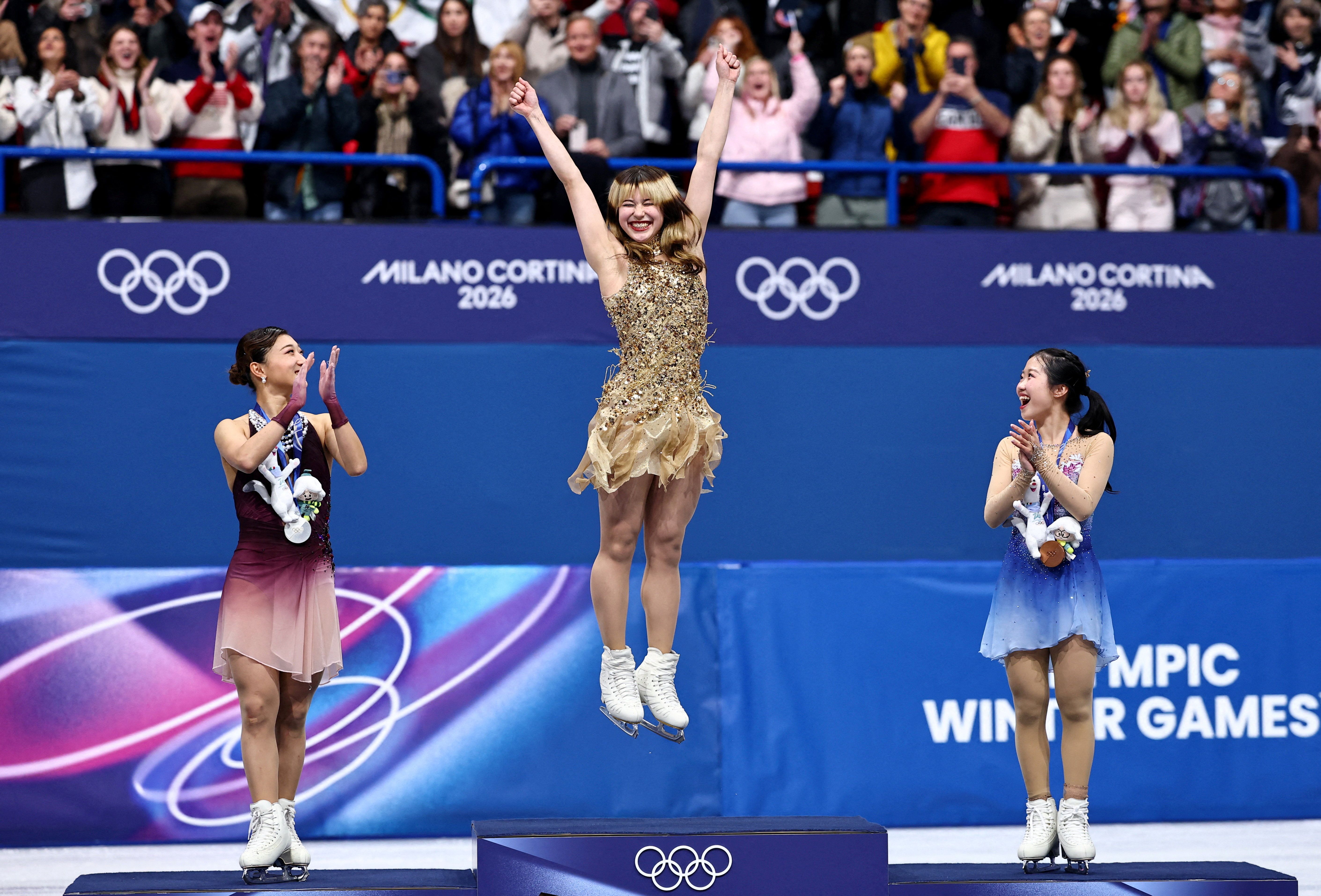 Gold medallist Alysa Liu of United States celebrates on the podium after winning the Women Single Skating with Silver medallist Kaori Sakamoto of Japan and Bronze medallist Ami Nakai of Japan
