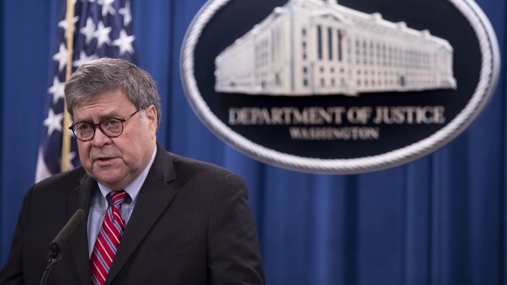 Photo of Bill Barr speaking against the backdrop of the DOJ seal