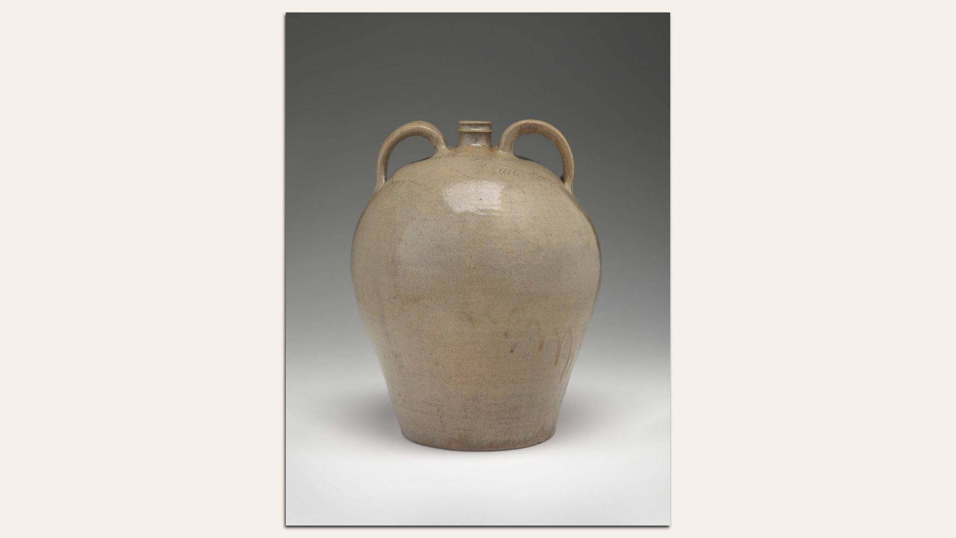 Beige ceramic vessel with a rounded body, a small neck, and two looping handles at the shoulders. Smooth glaze in neutral earth tones, set against a gray gradient background.