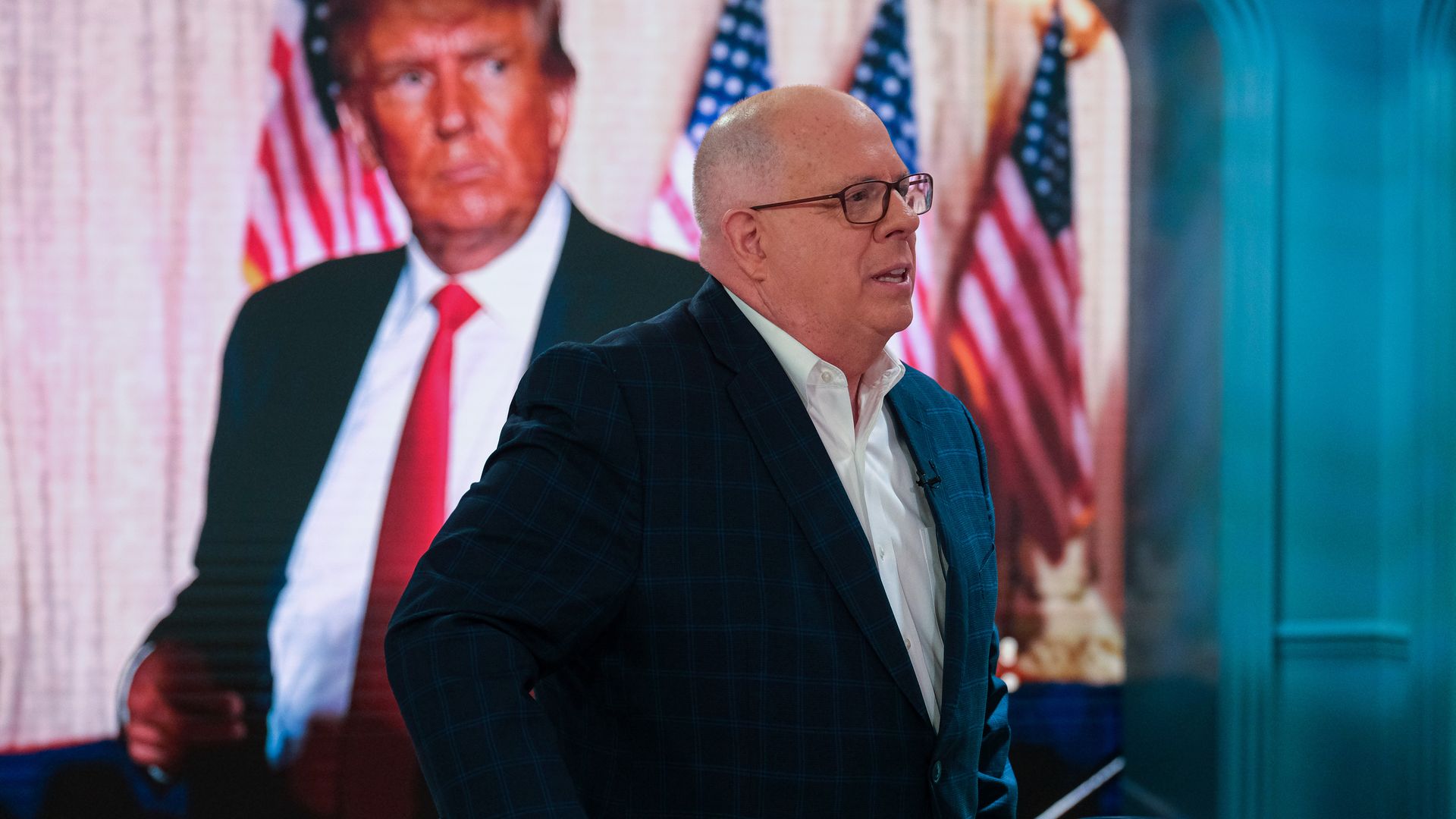 Larry Hogan in front of a picture of Trump