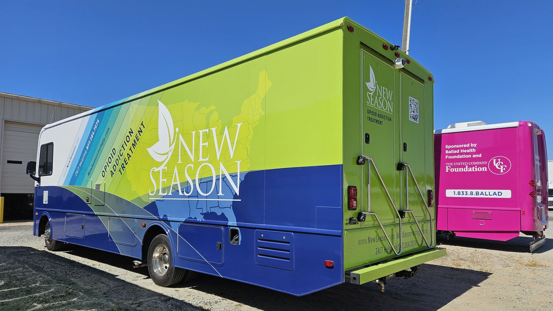 A mobile opioid addiction treatment vehicle labeled "New Season" with a blue and green design is parked beside a pink health foundation-sponsored vehicle in a gravel lot under a clear blue sky.