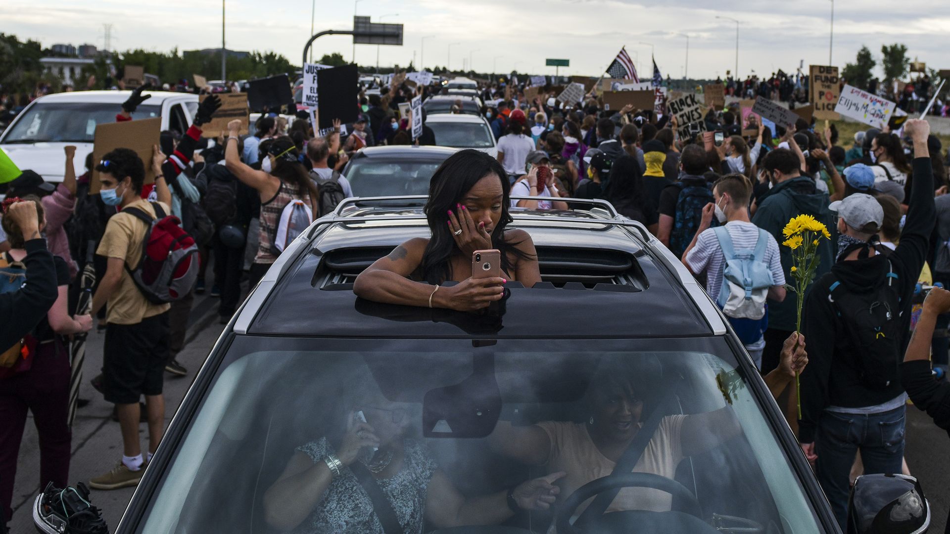 A  woman wipes away a tear while watching people shut down I-225 to protest the death of Elijah McClain on July 25, 2020 in Aurora, Colorado.