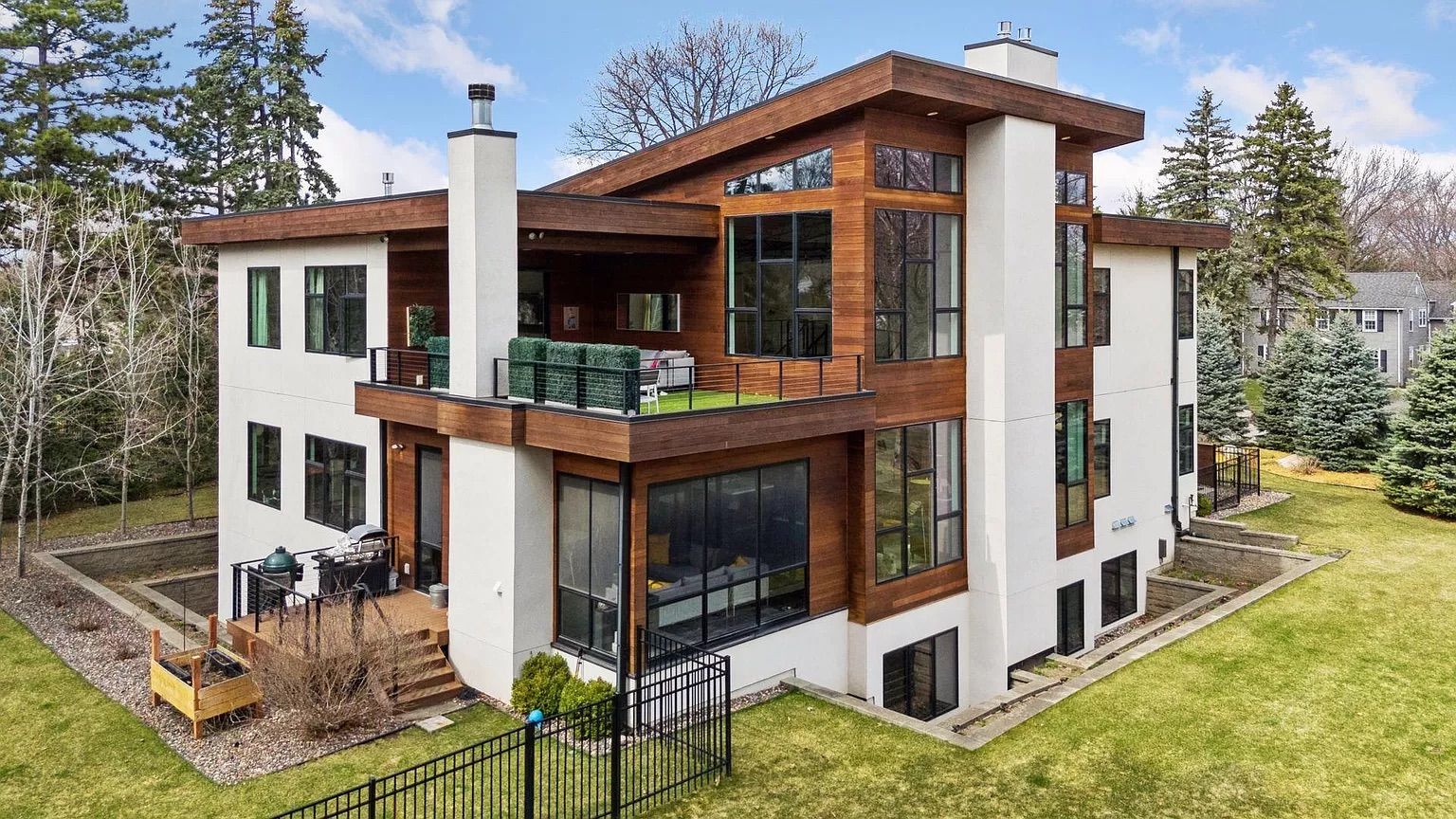 The exterior of a white and brown mansion with large windows.