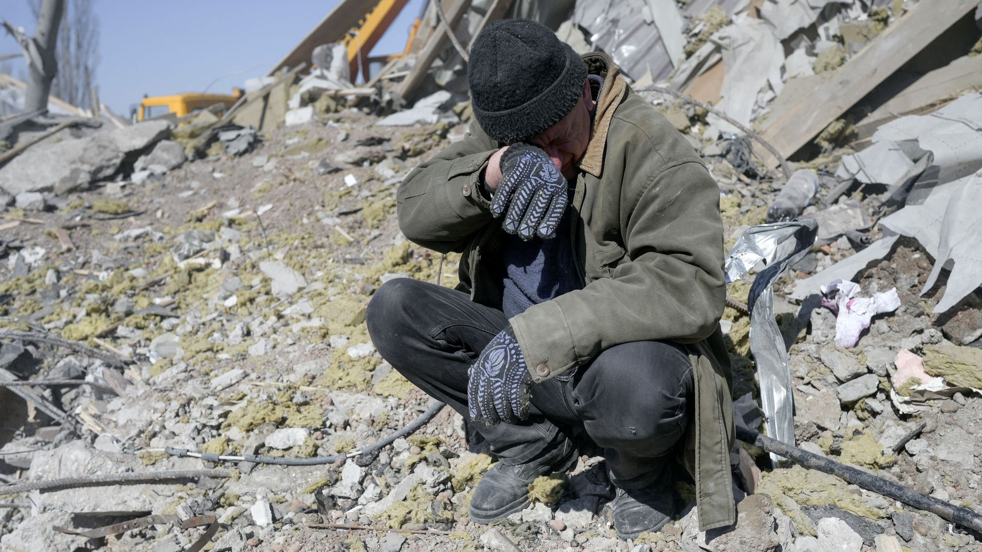A person is crying surrounded by rubble